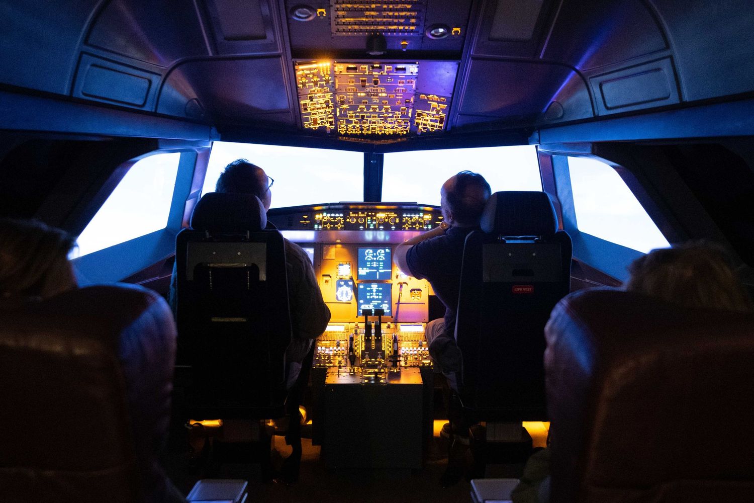 Dark cockpit interior with illuminated instrument panels and displays during night flight.