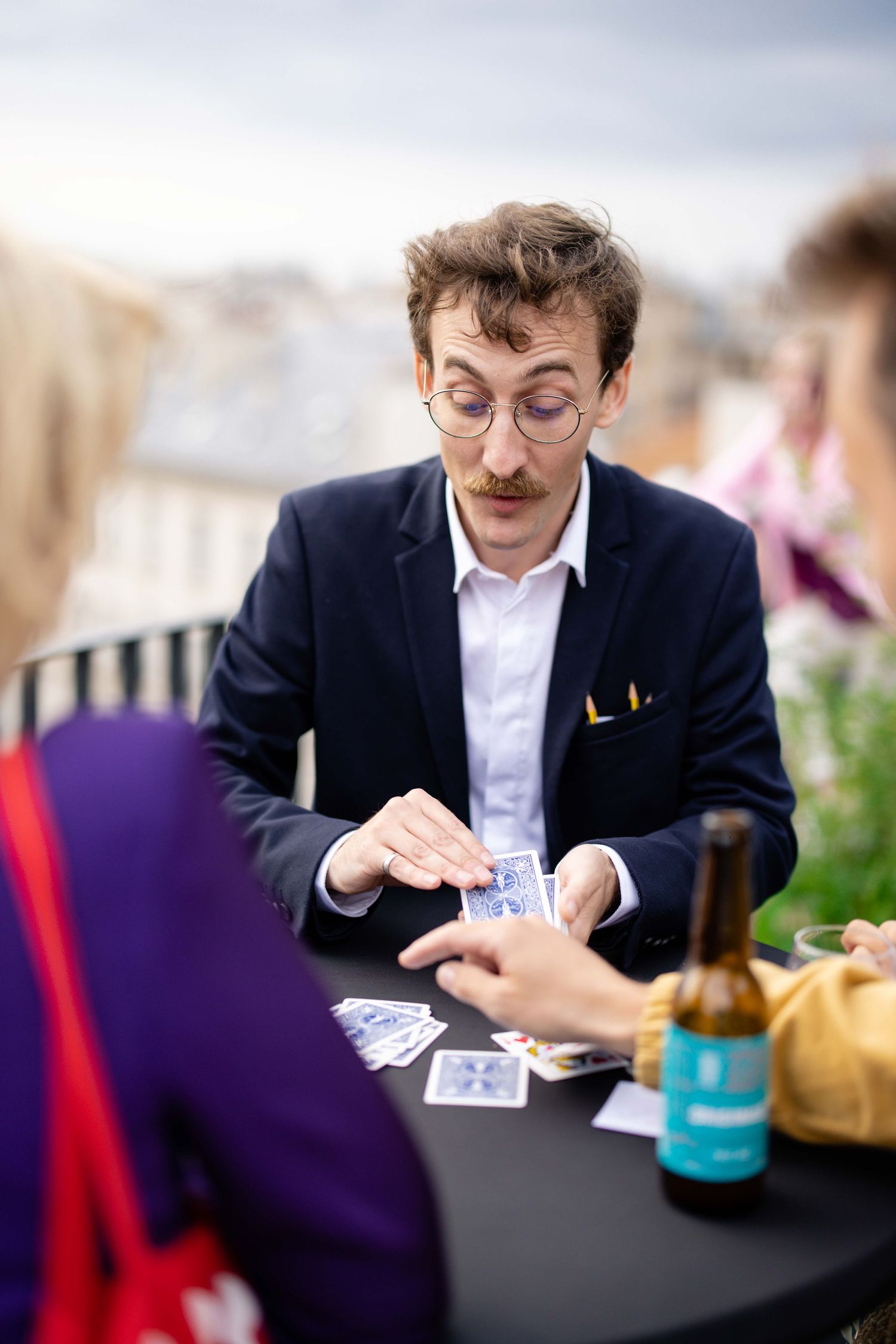 Person performing card tricks at a table during social gathering.