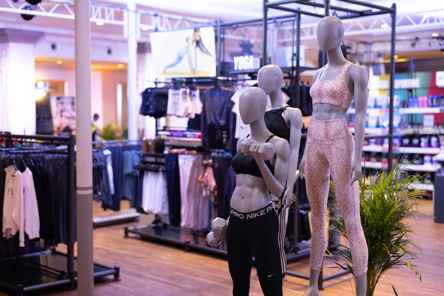Retail store interior showing clothing displays and mannequins in a modern shopping environment.