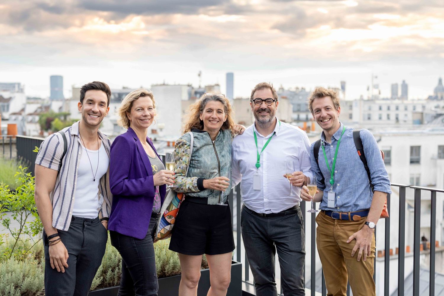 Group of people gathered on an outdoor terrace with city skyline views at sunset.