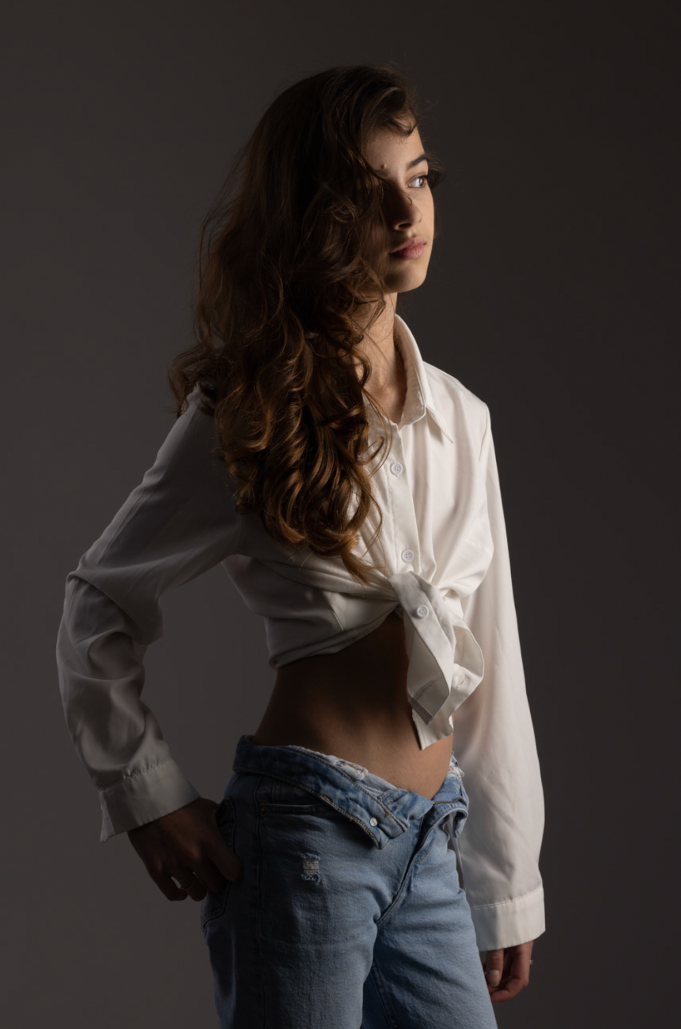 Artistic fashion portrait series showing a white button-down shirt and jeans in dramatic lighting against dark background.