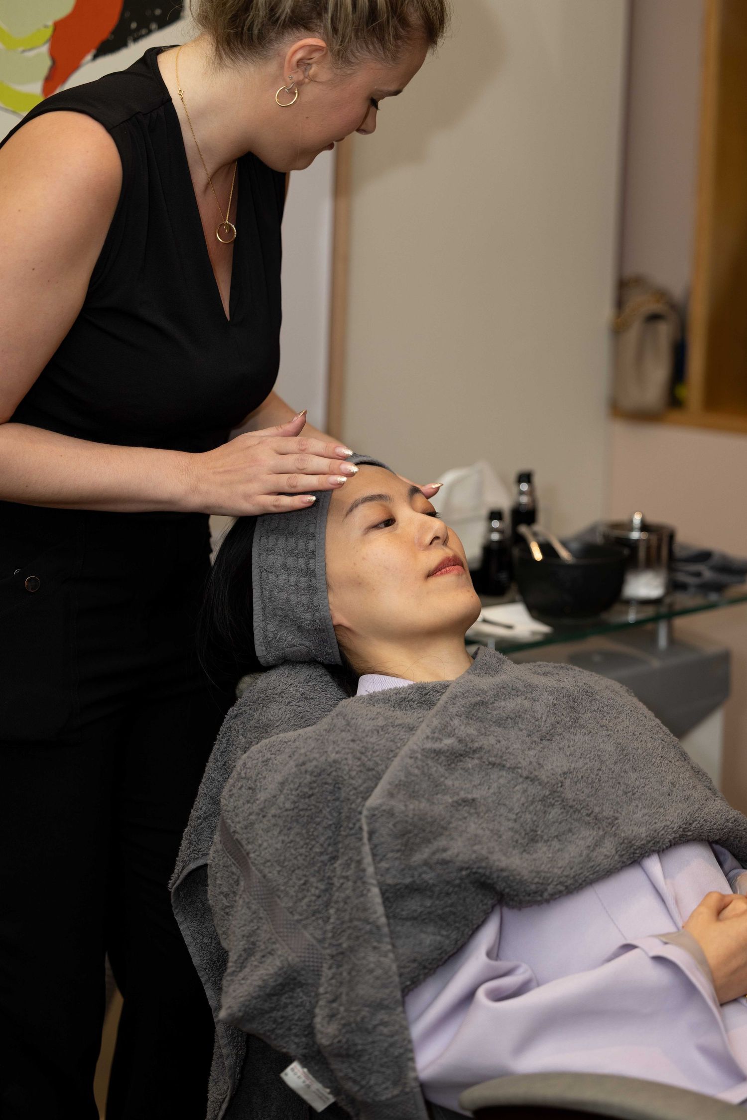Spa treatment session showing relaxation service with grey towel.