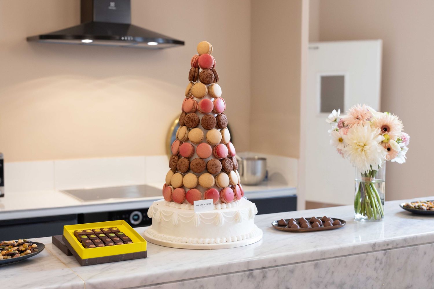 Elegant dessert display featuring macarons and floral arrangements on marble counter.