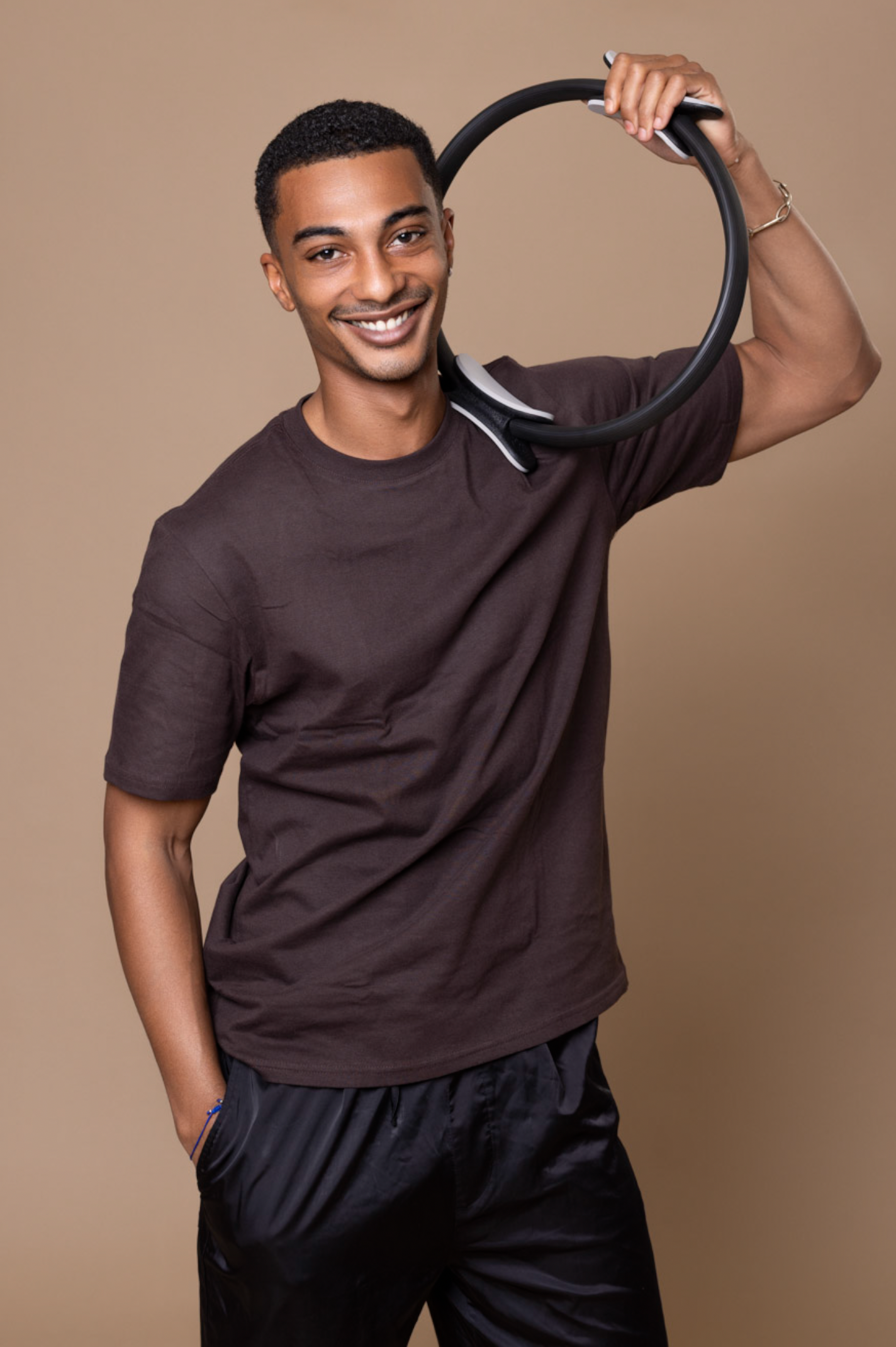 A series of studio portraits showing someone wearing a brown t-shirt and black pants against a beige backdrop.