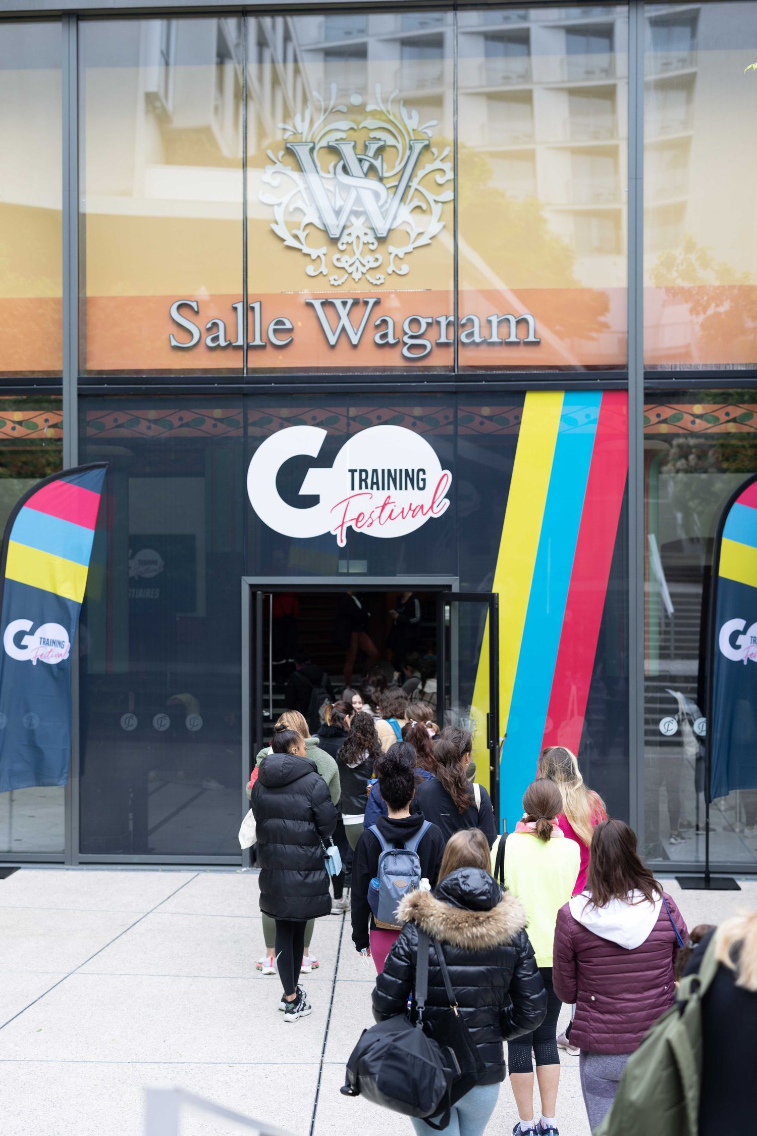 People queue outside Salle Wagram entrance with Training Festival banners and decorations.