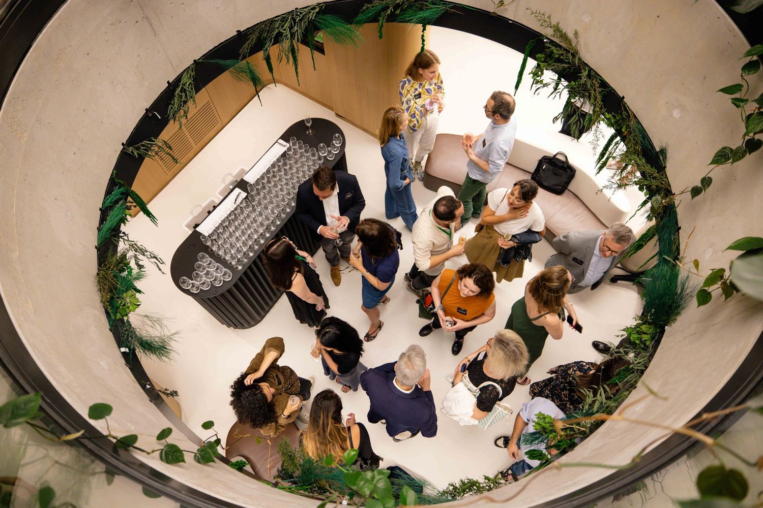 Overhead shot of business gathering in circular space decorated with plants and modern furniture.