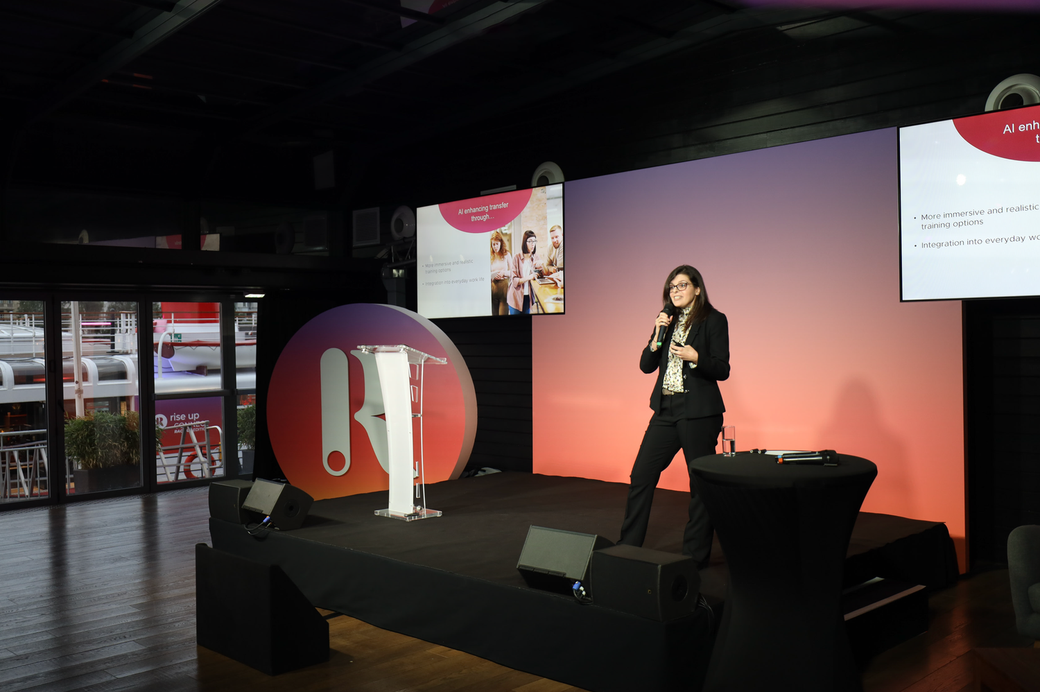 Conference stage setup with large projection screen and red accent lighting.