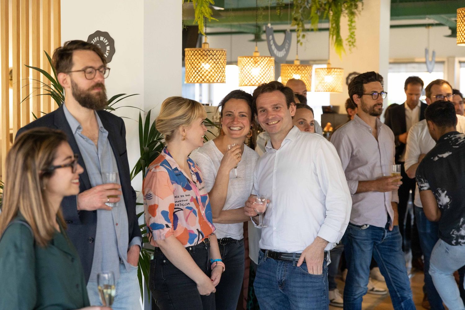 Attendees mingling and socializing at a professional networking event with decorative plants.