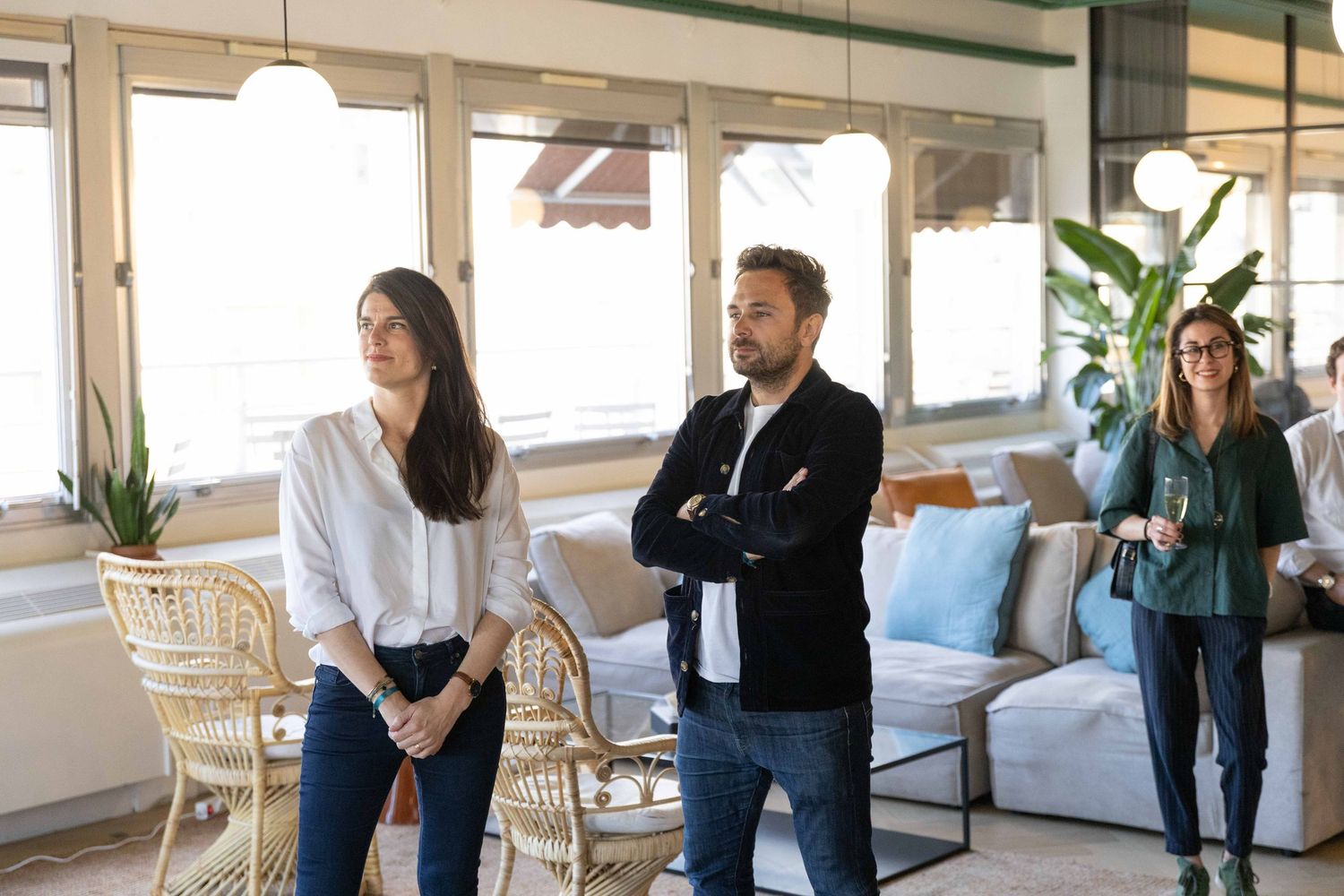 Business professionals networking and mingling in a modern office space with pendant lighting and plants.