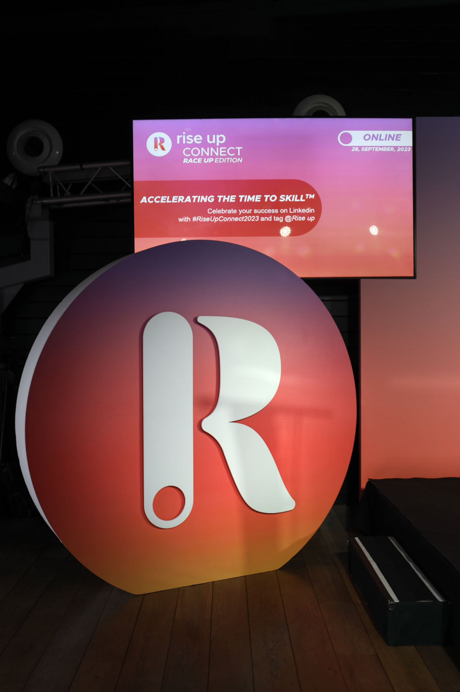 Large illuminated red letter R logo display on stage with gradient lighting effects.