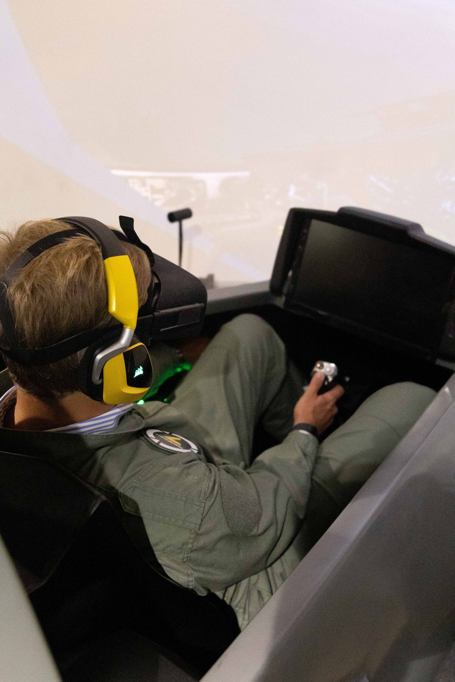 Person wearing yellow ear protection using a flight simulator.