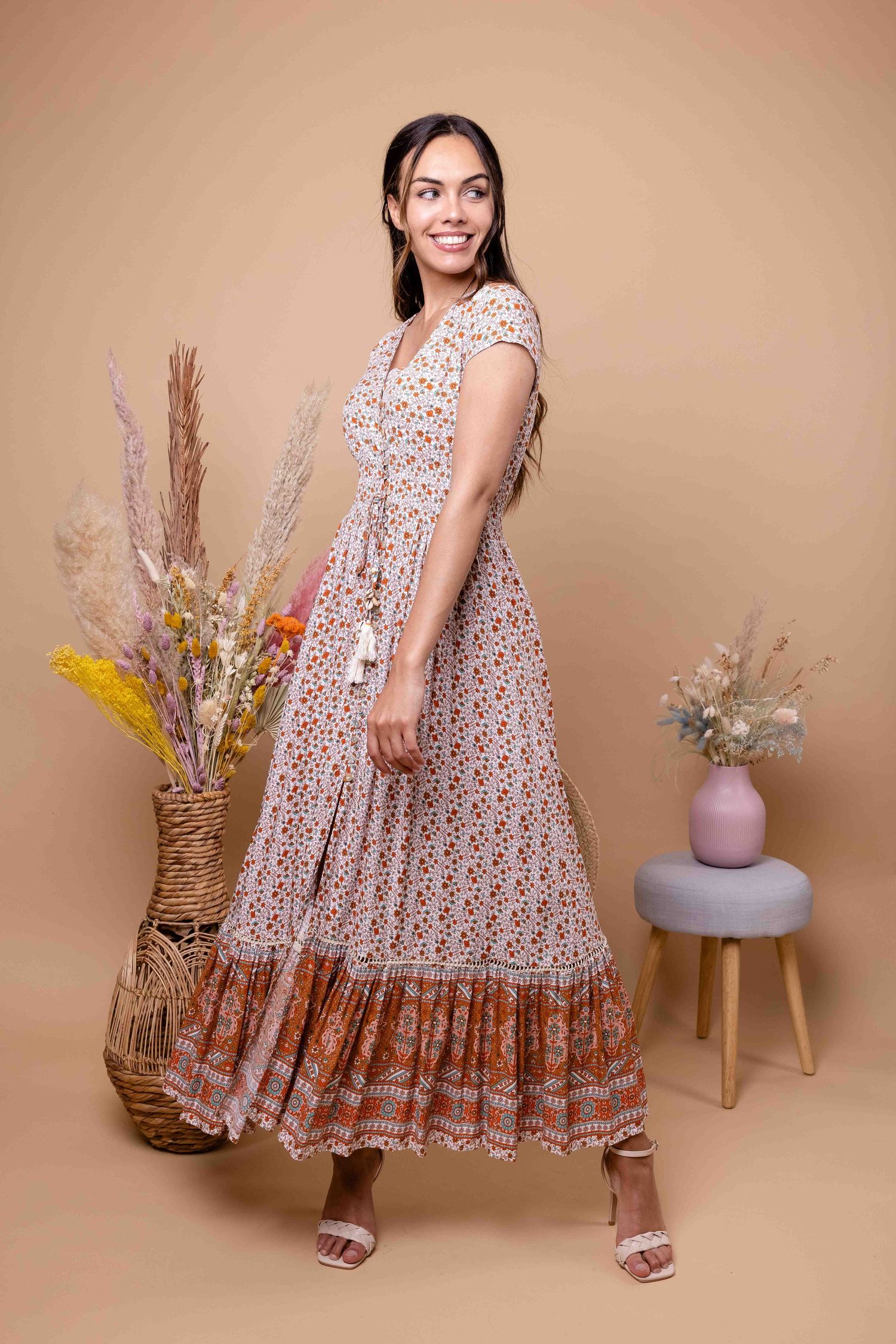 Robe longue de style bohème avec motif complexe et jupe à plusieurs niveaux présentée dans un cadre domestique décontracté.