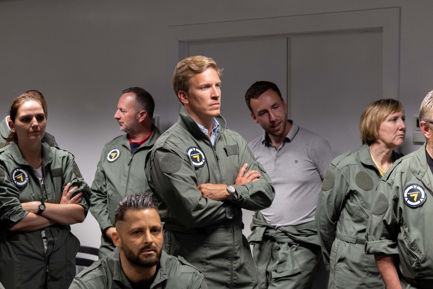 Military personnel in flight suits gather for a briefing session in an aircraft hangar.