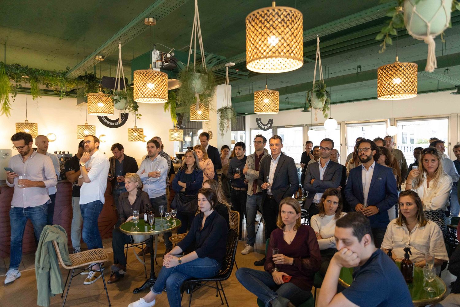 Audience members seated in rows at a corporate event with woven pendant lights overhead.