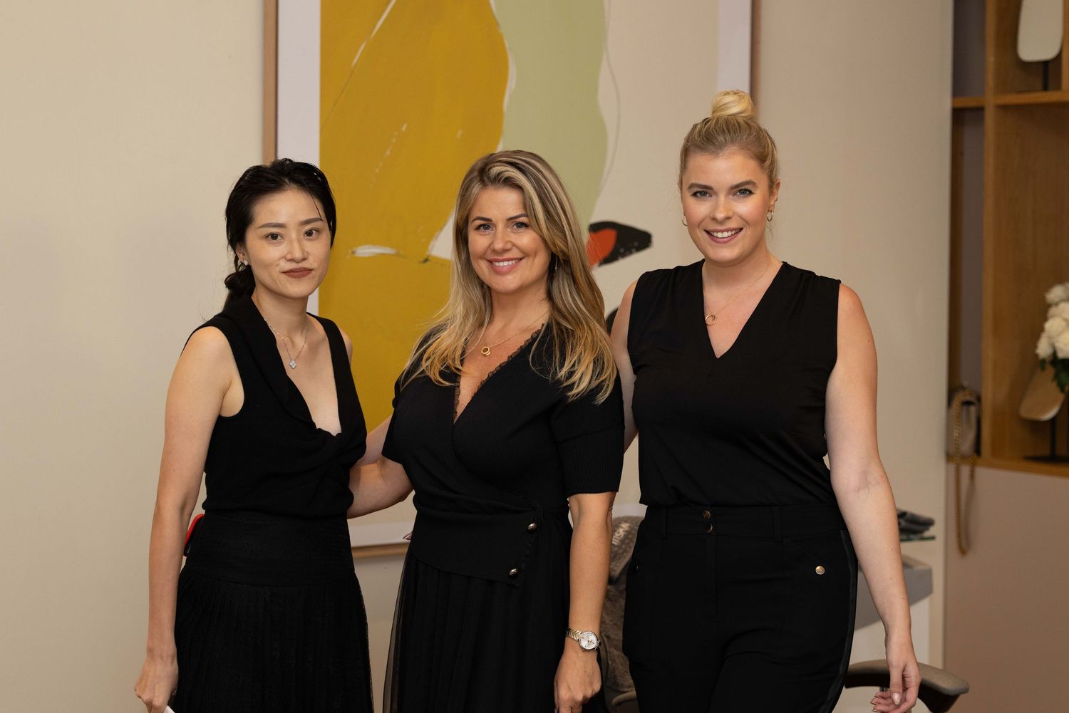 Beauty professionals in black attire gather at a salon event.