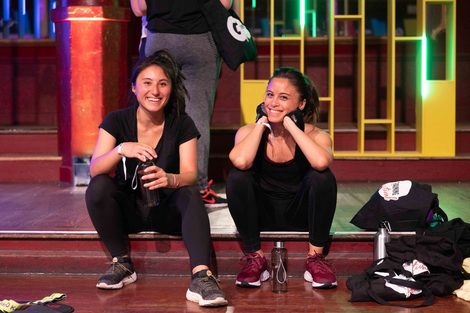 Participants exercising on a stage with vibrant red and green lighting during a fitness event.