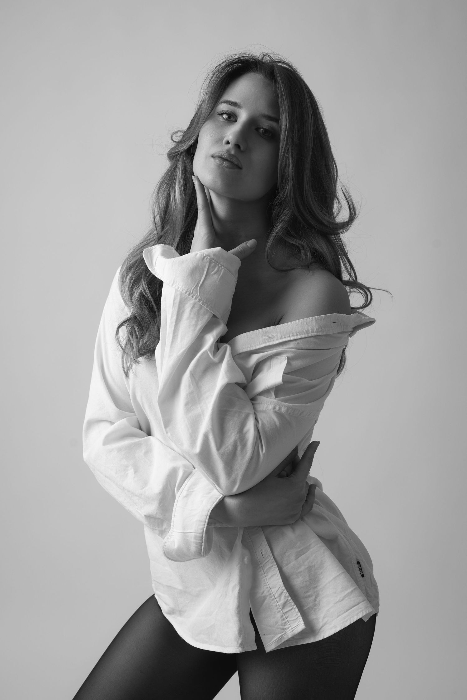 Black and white fashion portraits of a person in a white button-up shirt posing against a light background.