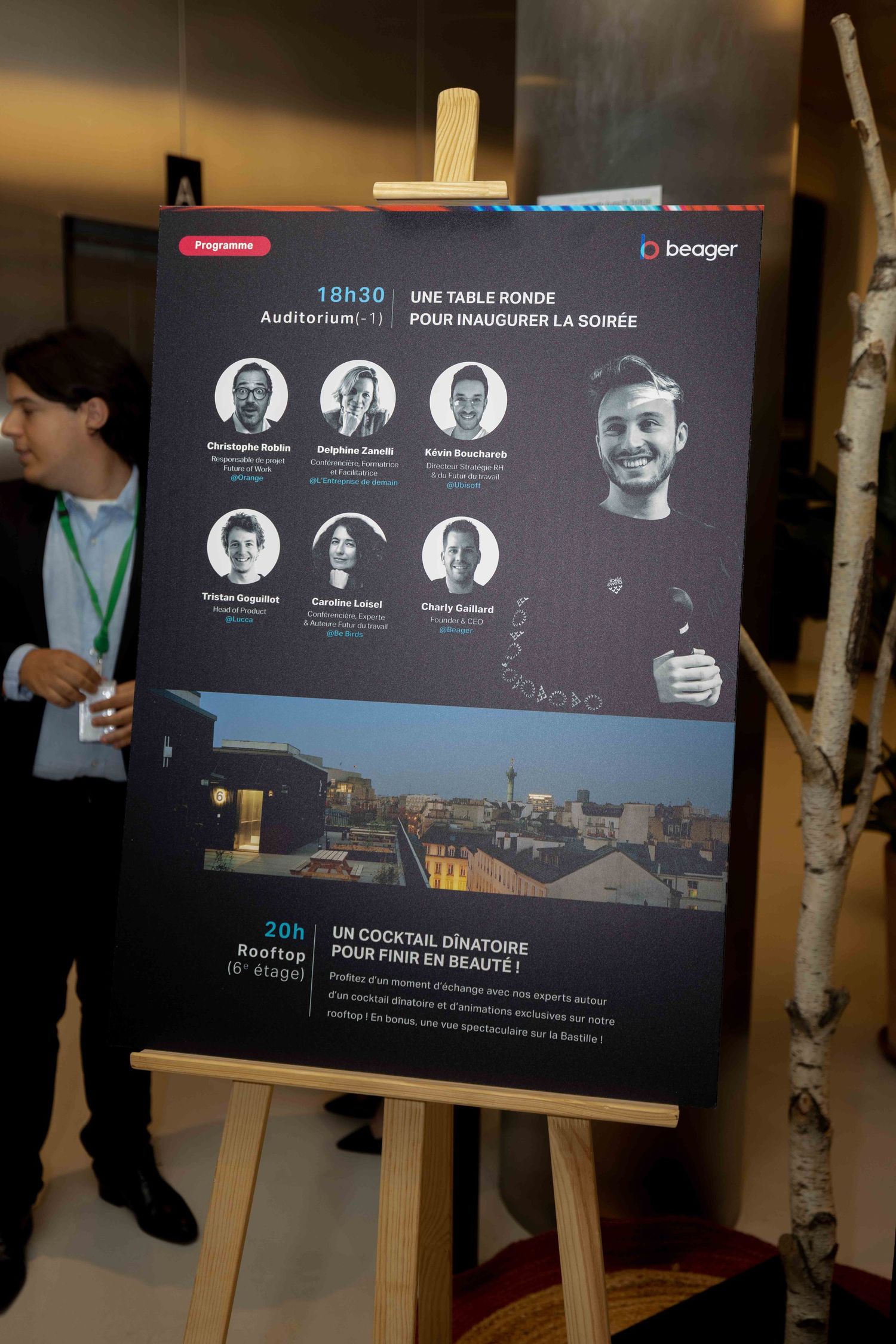 Digital presentation display showing speaker profiles and event schedule on a dark screen.