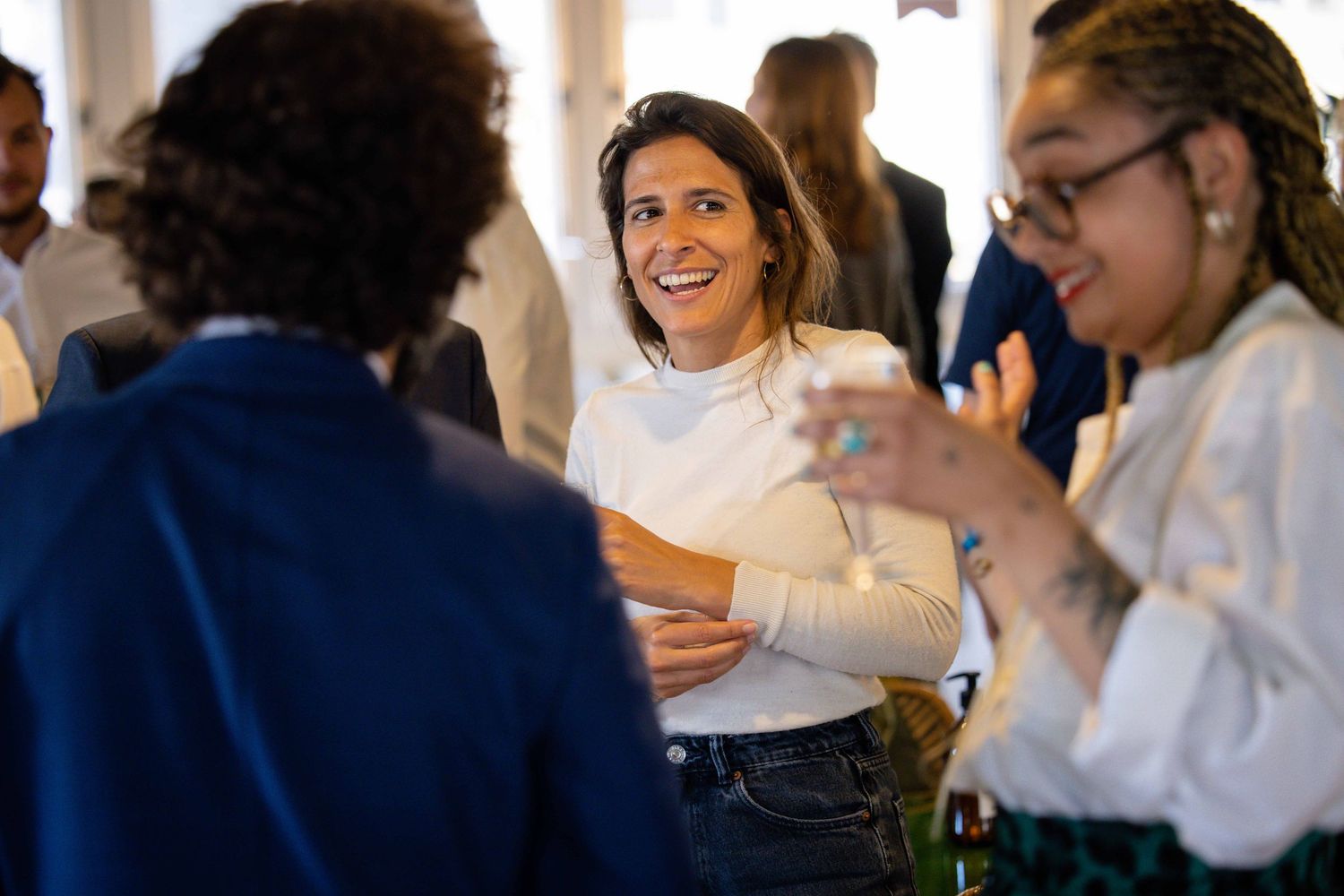People engaged in conversation at a professional networking event with bright interior lighting.