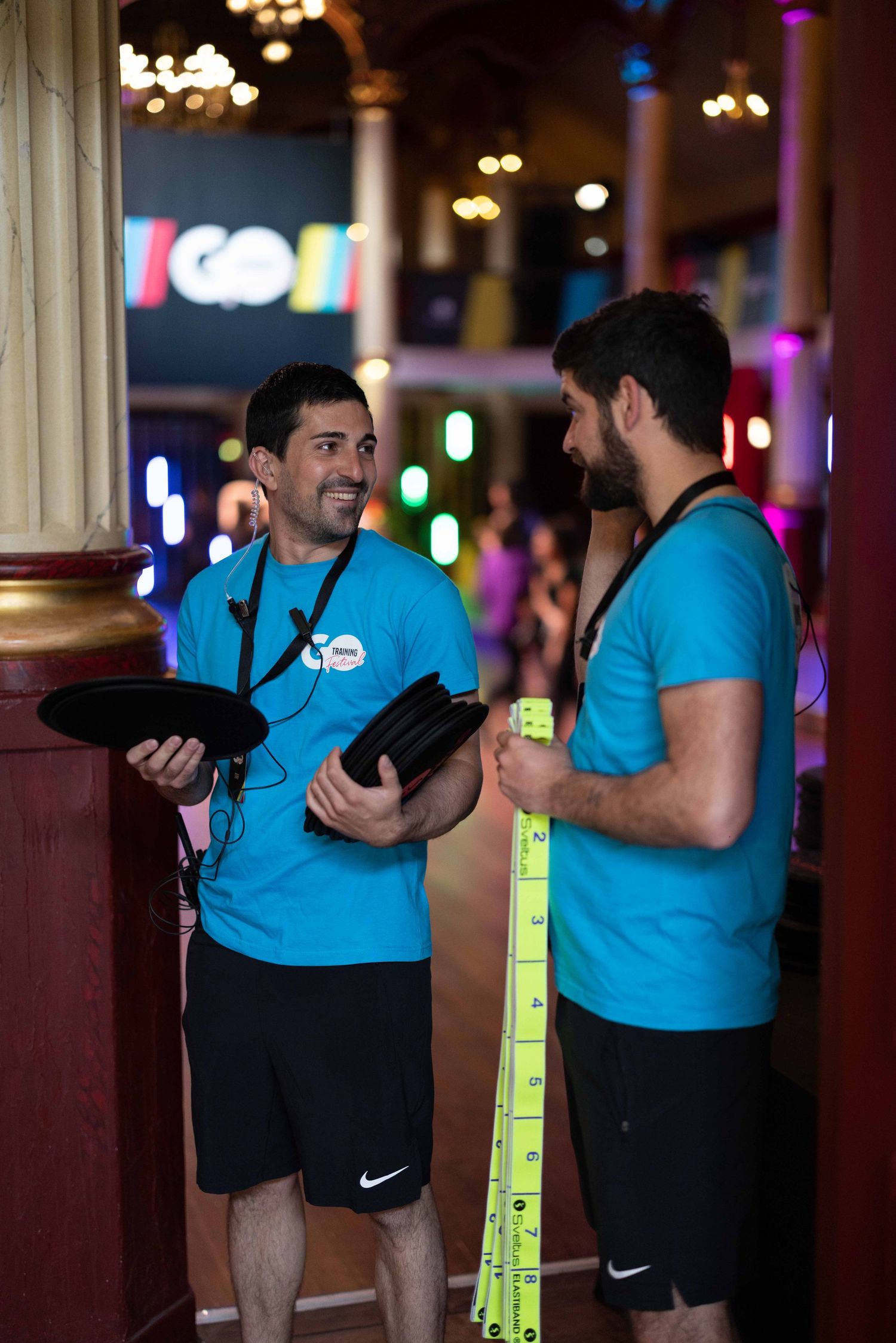 Staff members in blue uniforms discuss event details while holding equipment.