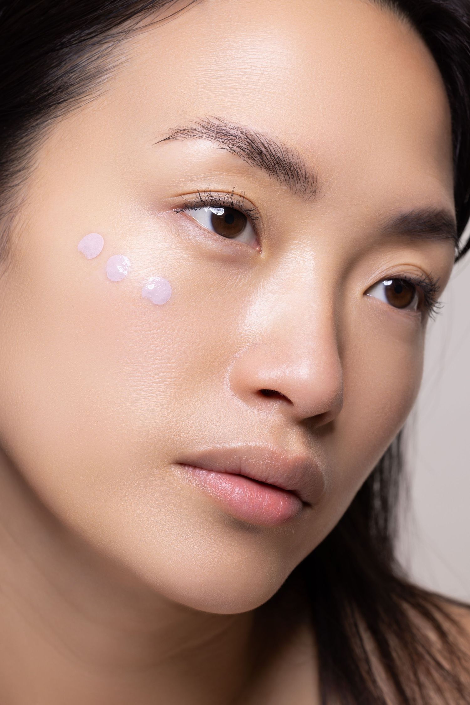 Photo beauté épurée avec des points décoratifs sous les yeux et un maquillage minimal.