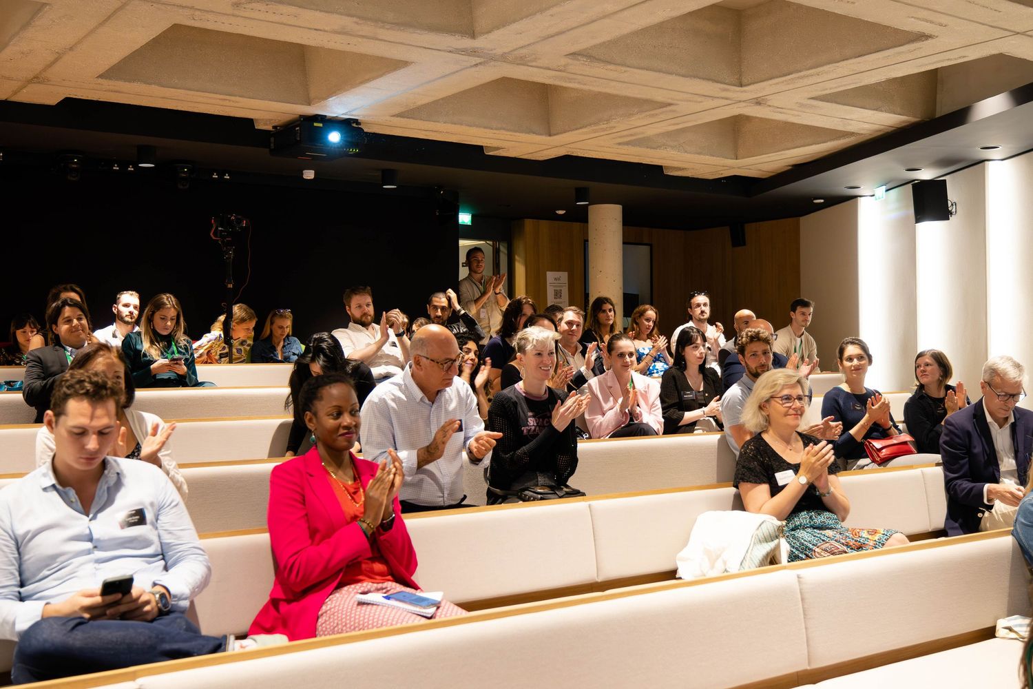 Wide angle view of filled conference auditorium during presentation.