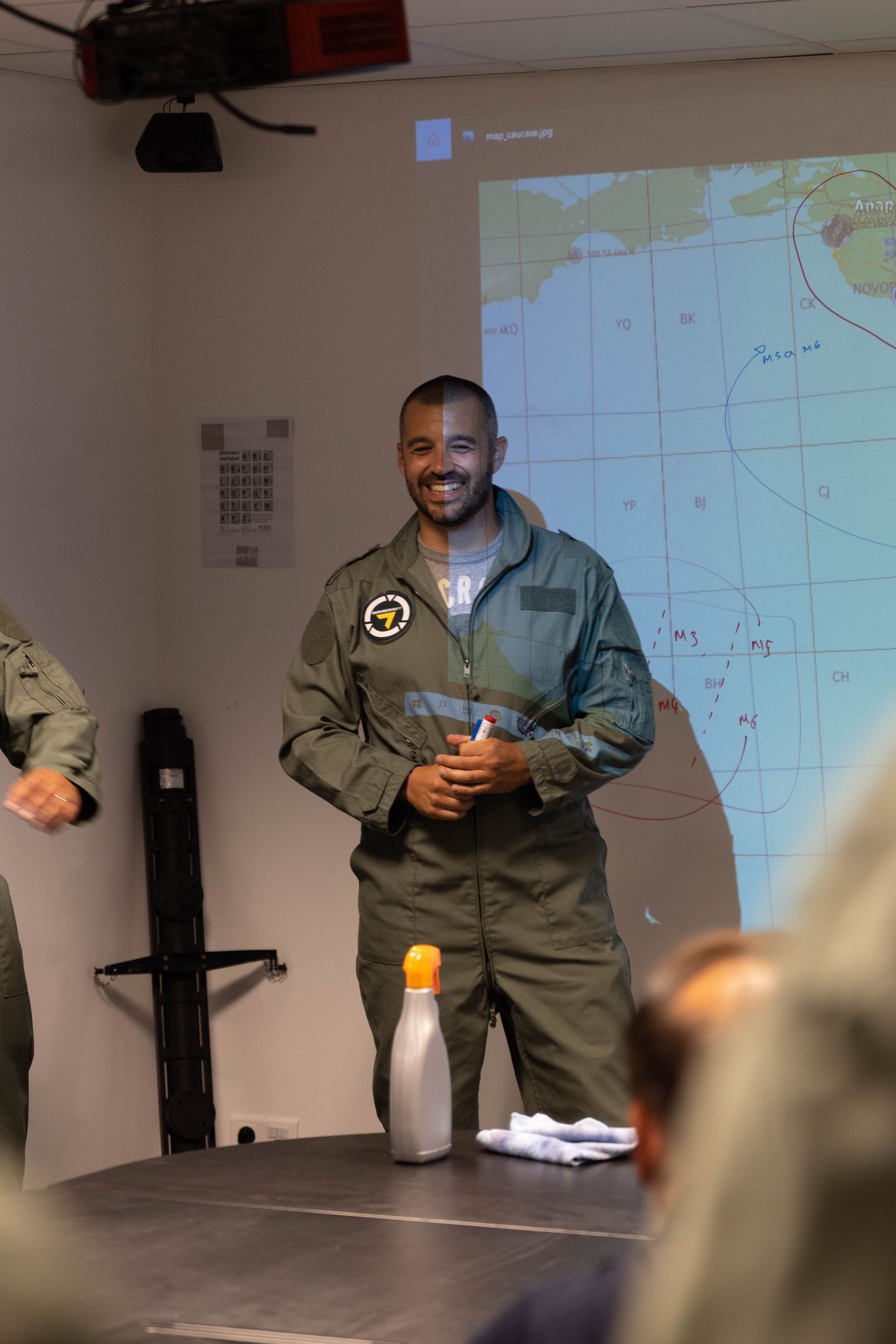 Military briefing room with projected maps and geographical data on display.