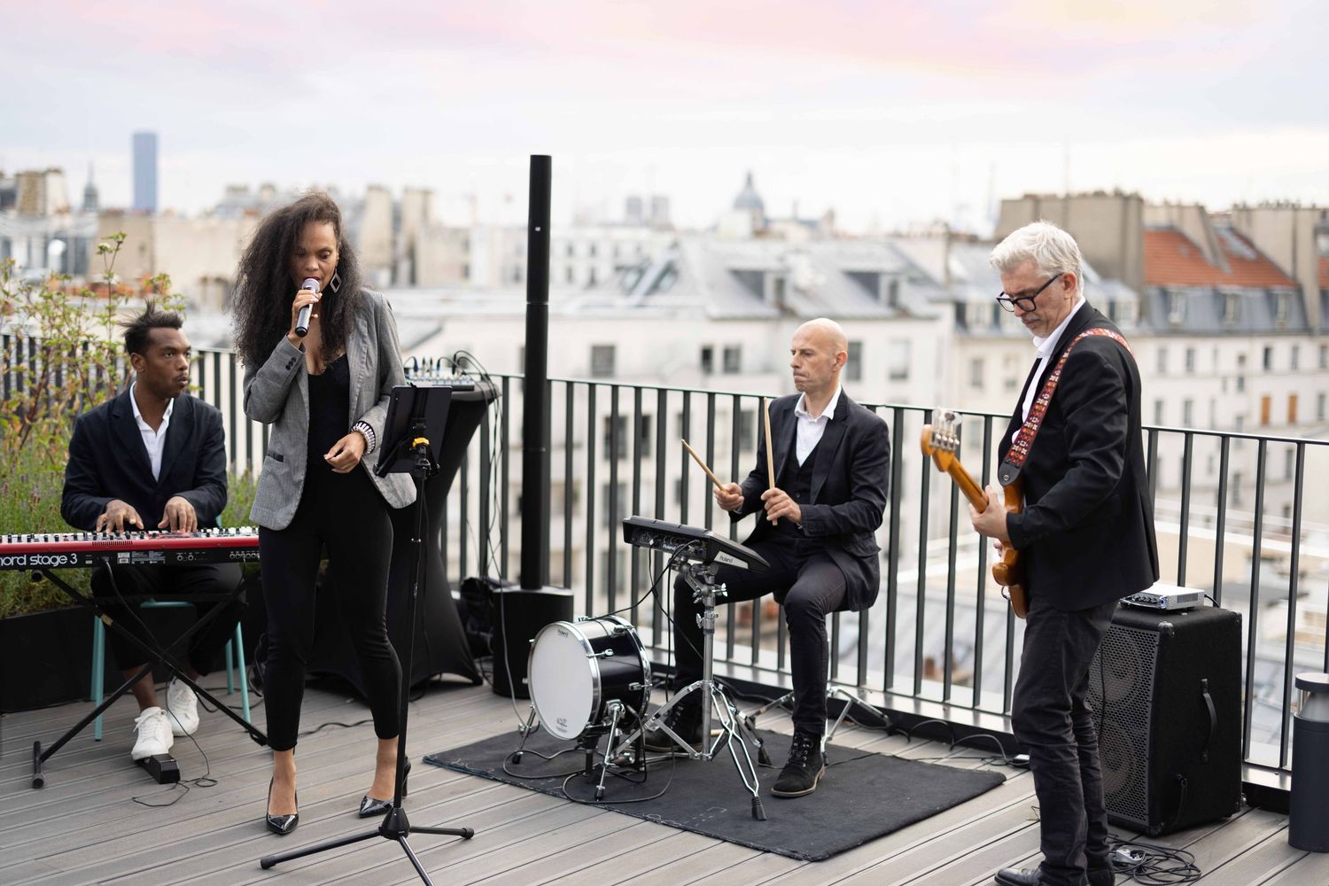 Live band performing on a rooftop terrace with city skyline in background.