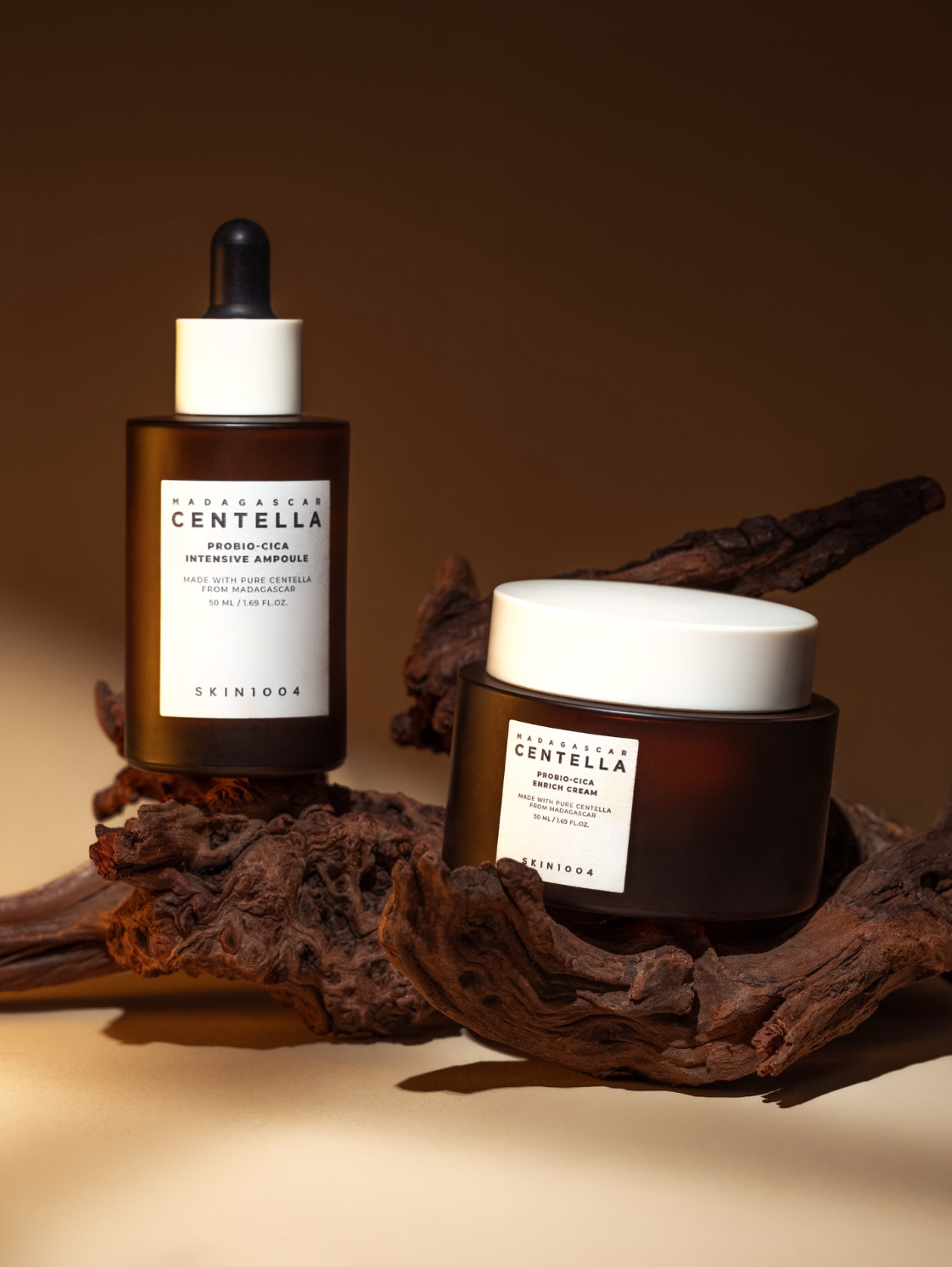 Skin1004 Centella Probio-Cica serum and cream skincare products displayed on driftwood against warm brown background.