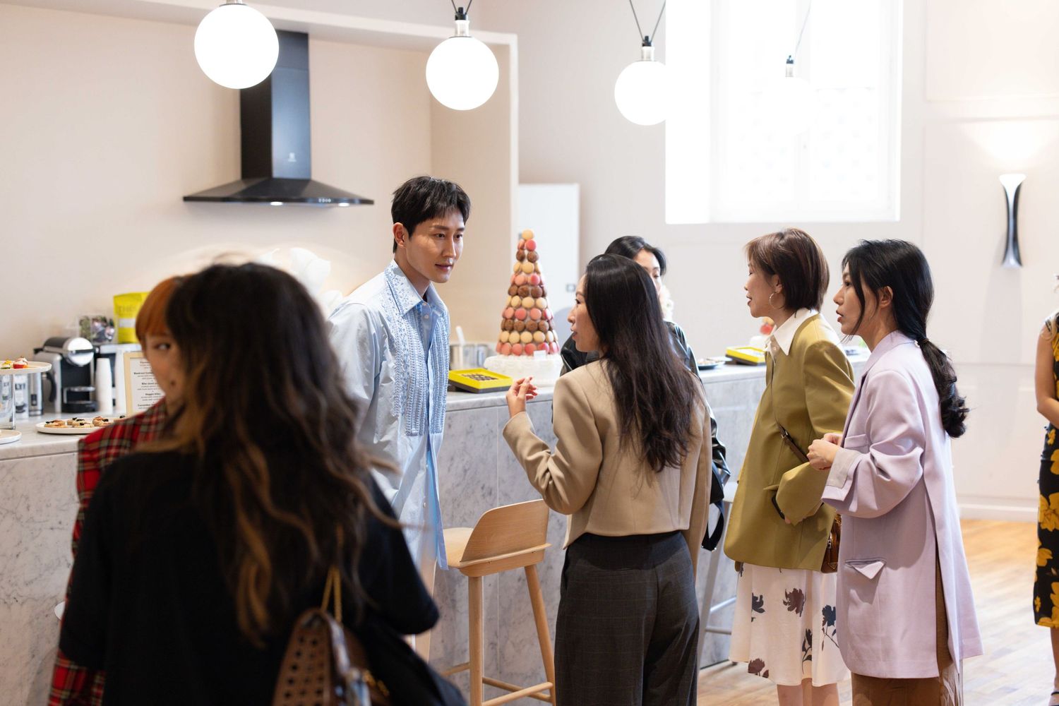 People gathering in bright modern space with pendant lighting.