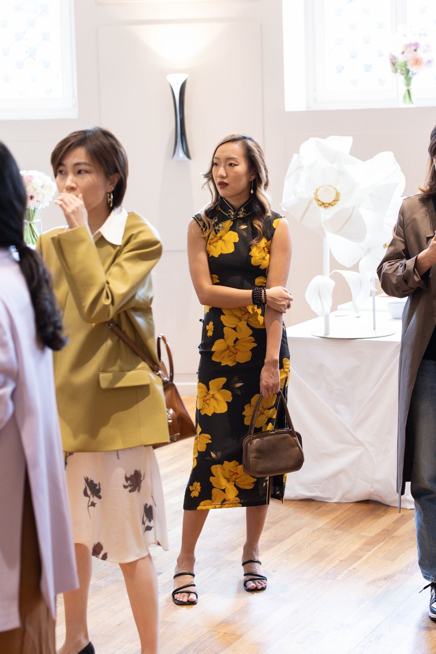 Group mingling at an indoor event with yellow floral decorations visible in the background.