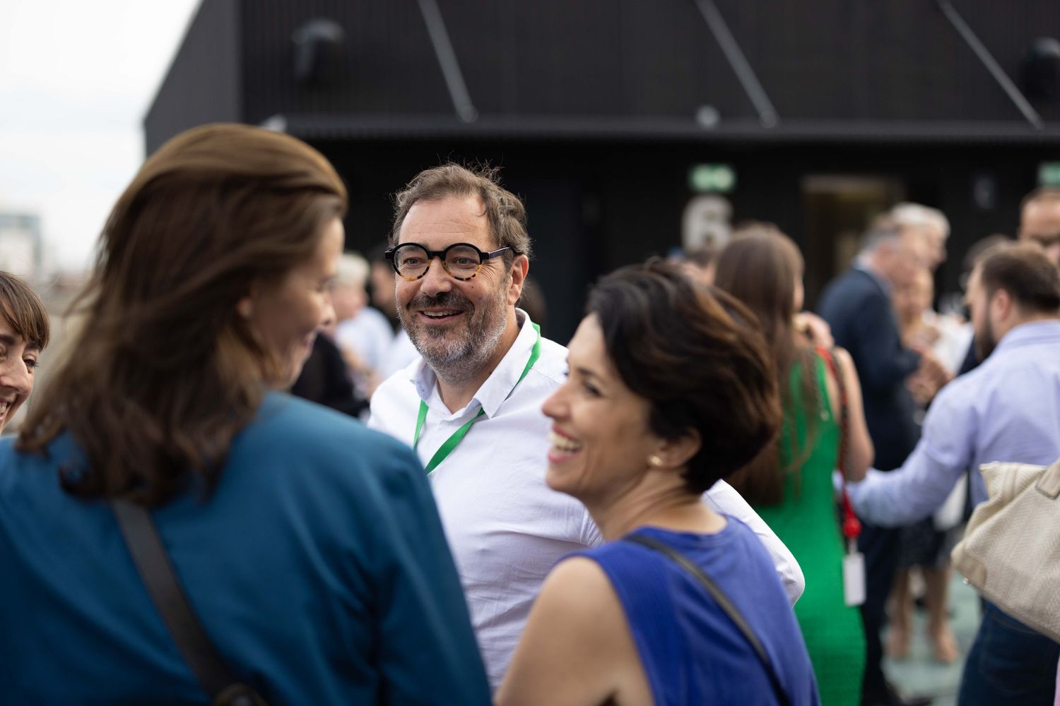 Business professionals engaged in animated conversation at an outdoor networking event.