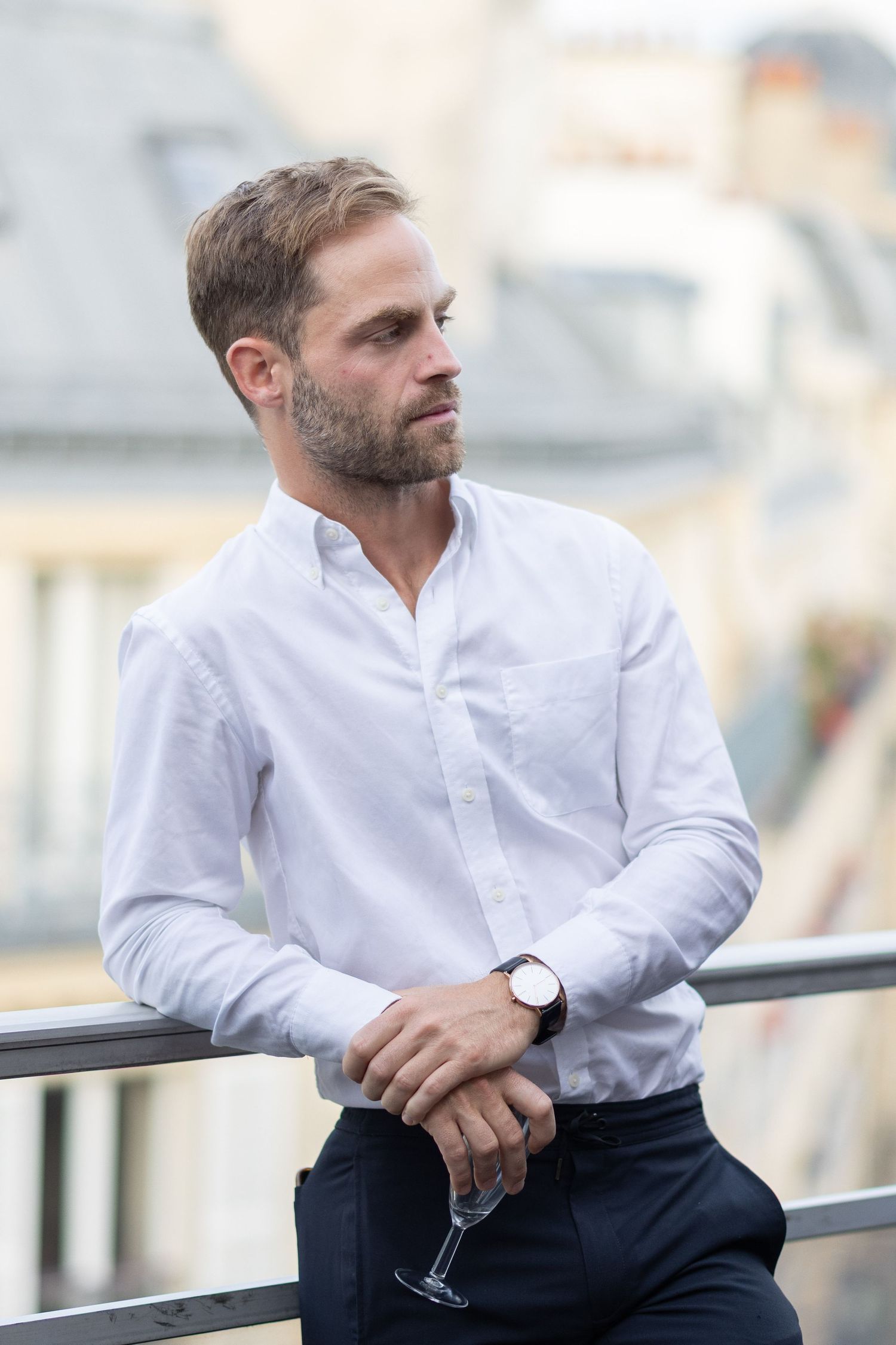 Person in white shirt leaning against railing while holding a drink.