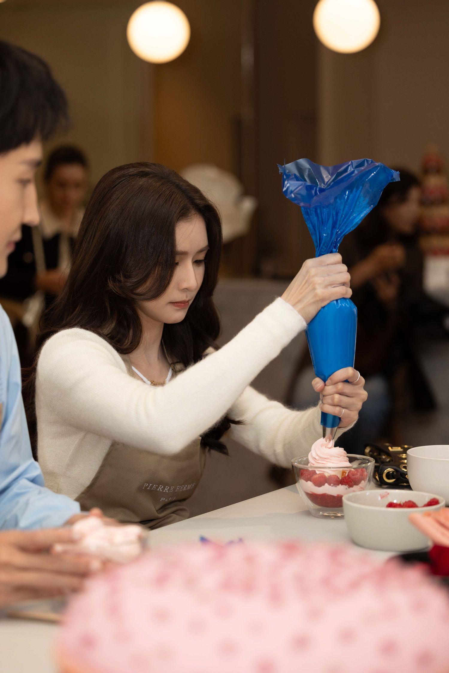 People holding blue pastry bags while participating in a dessert decorating class.