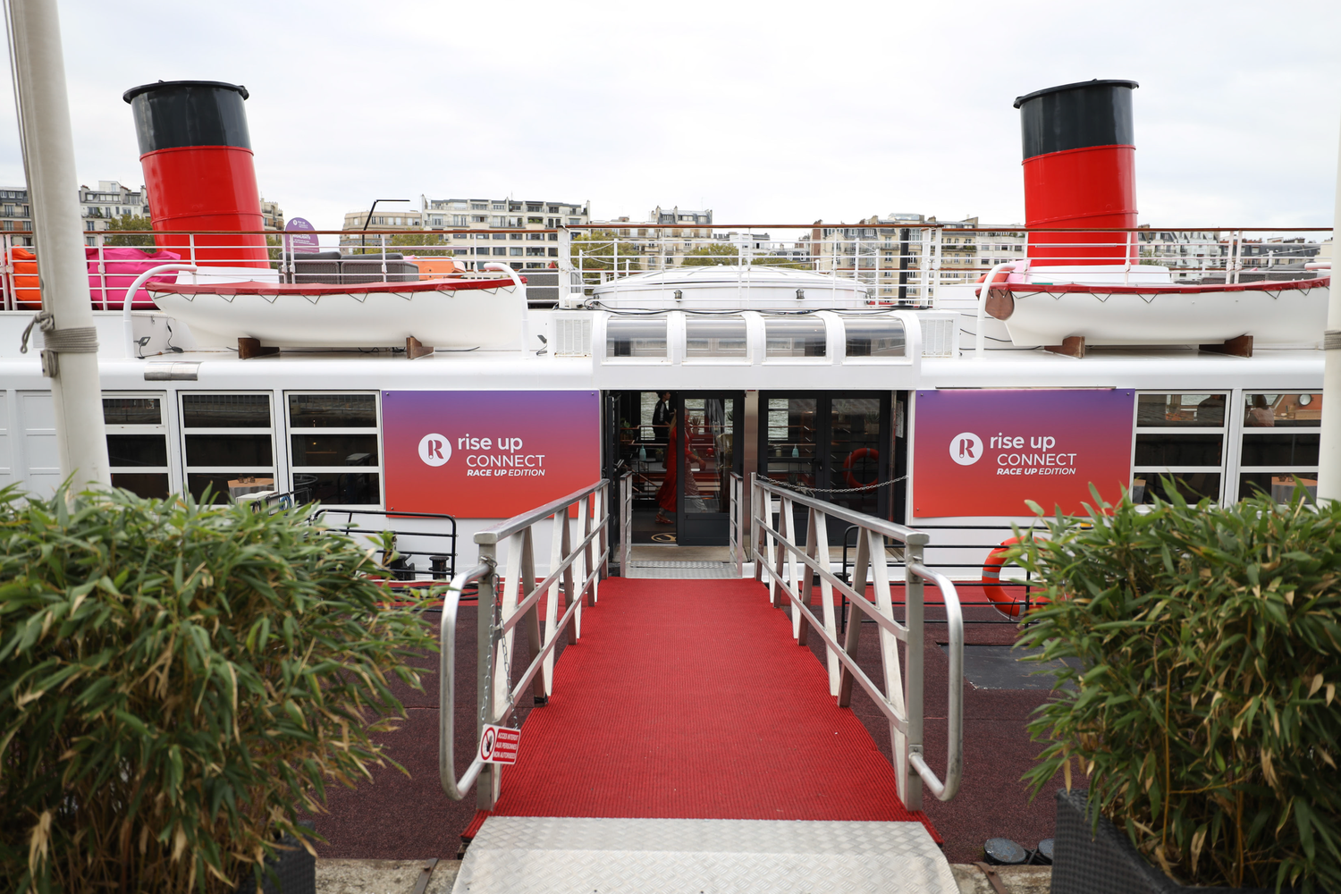 Red carpeted outdoor venue setup with branded banners and bamboo plants.
