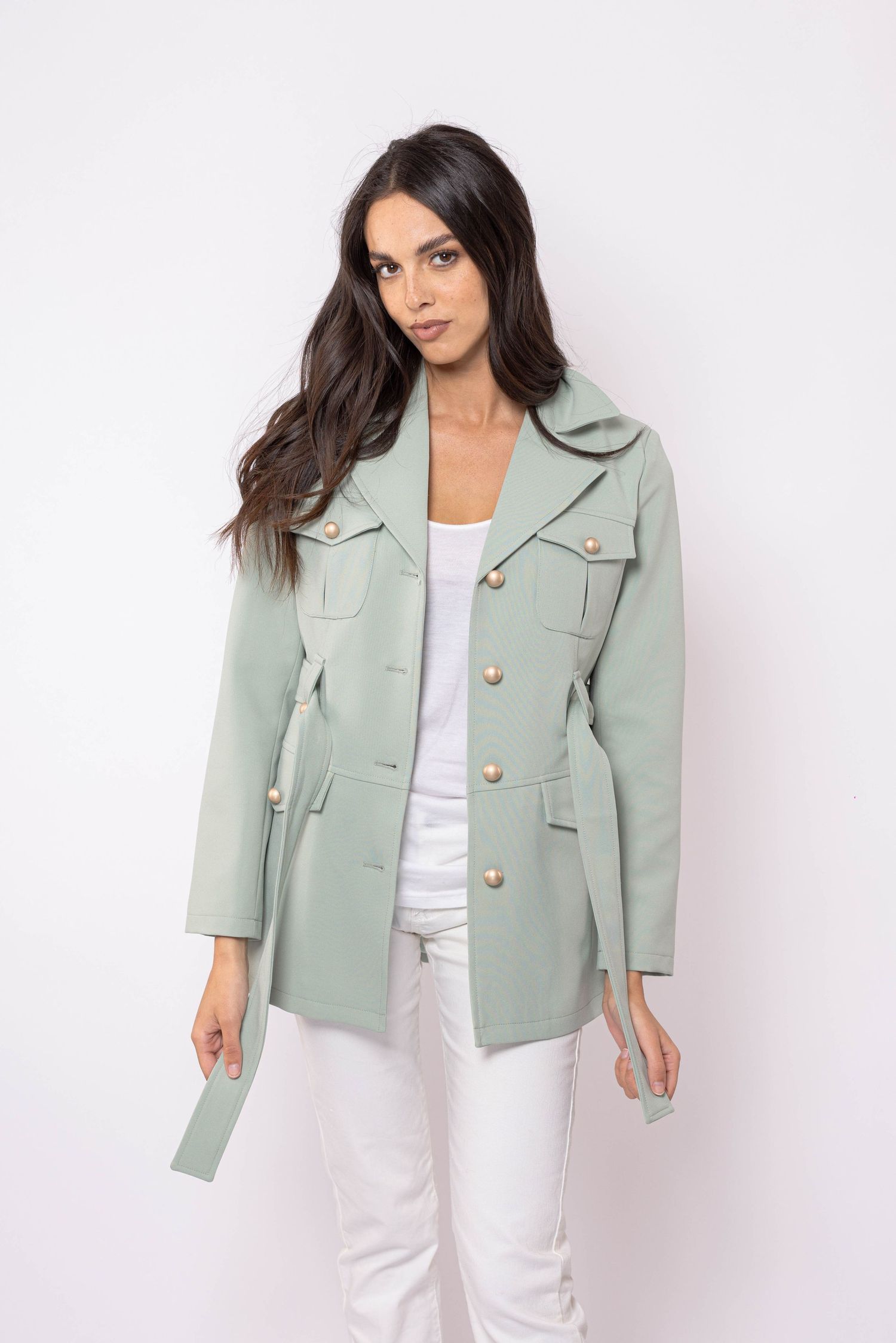 Veste utilitaire vert sauge associée à un pantalon blanc en studio.
