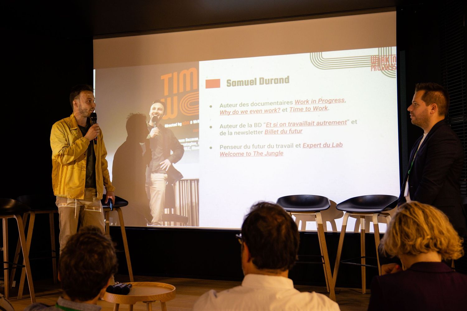 Wide view of presentation screen and stage setup during business conference.