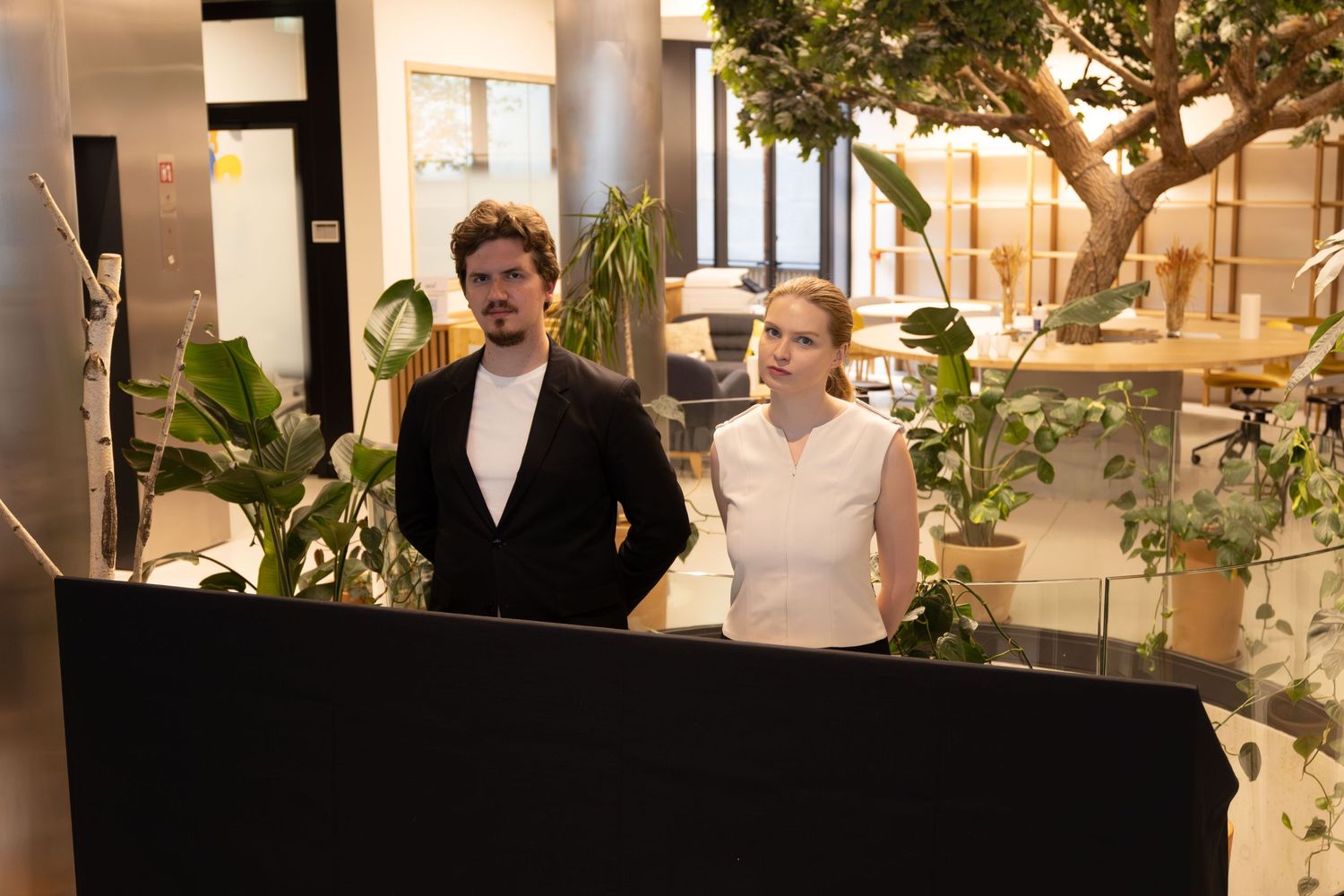 Modern office interior with white columns, plants, and natural lighting for a professional gathering.