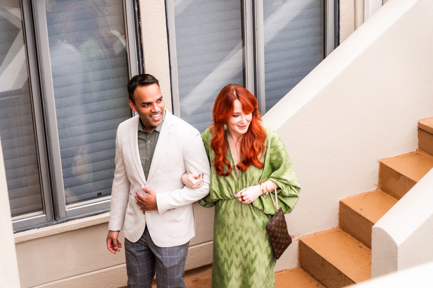 A couple walks up white stairs at a formal event.