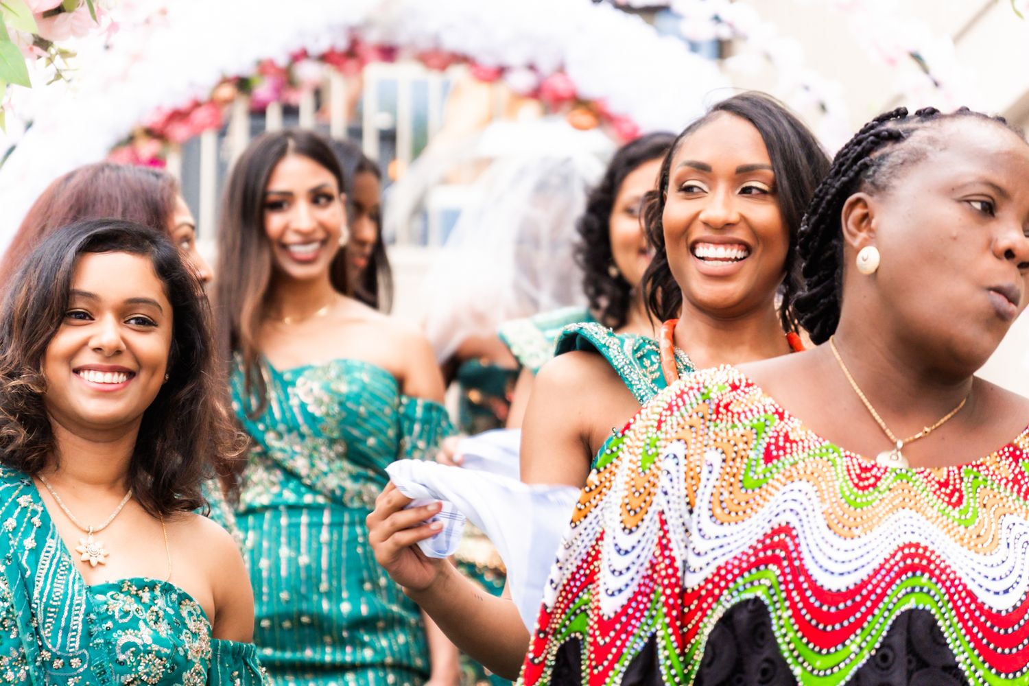 Group of wedding guests in colorful dresses enjoying a celebration outdoors.
