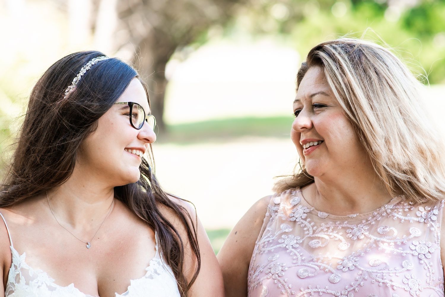 Two wedding guests share a candid moment of laughter outdoors.