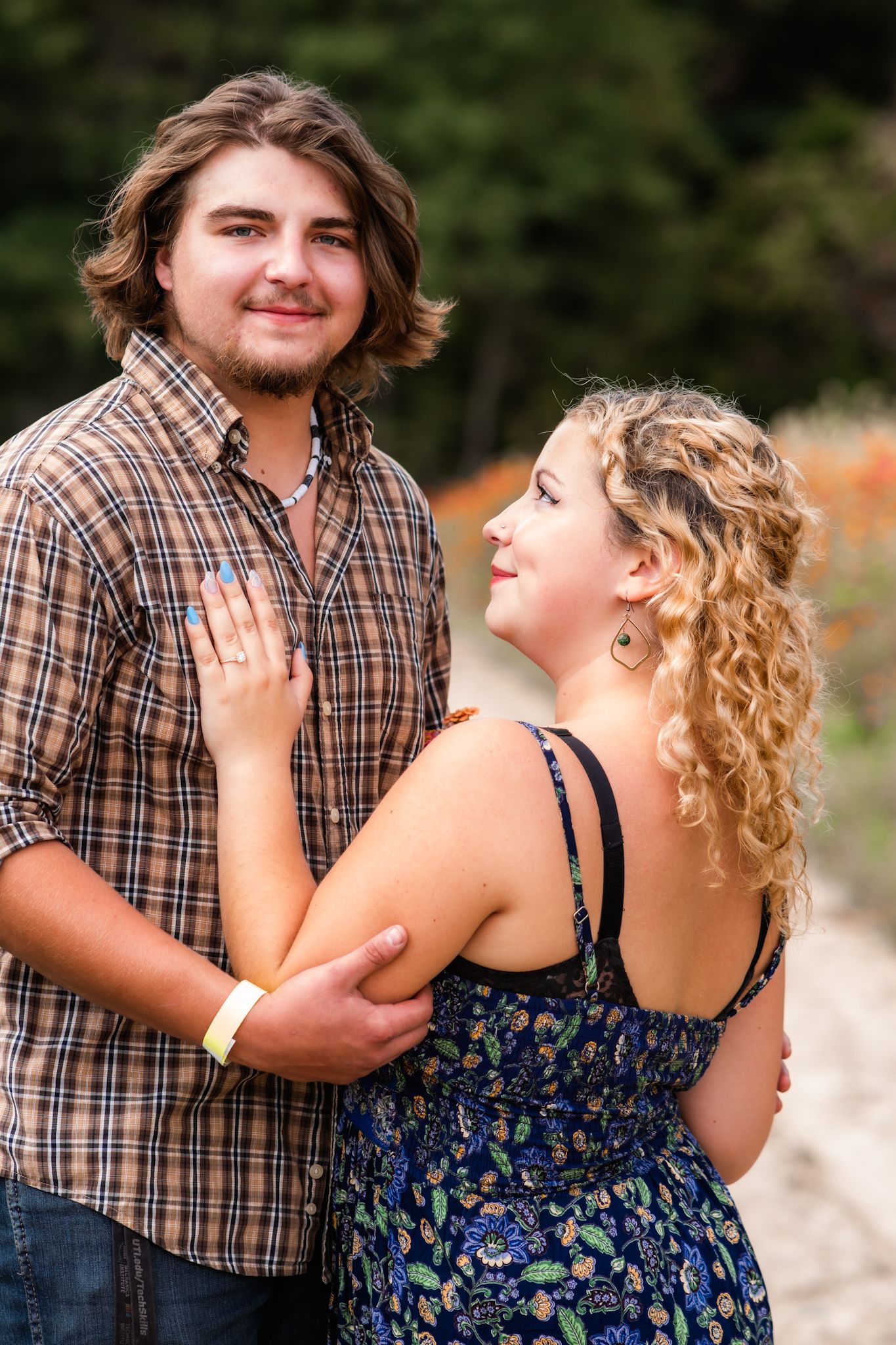 A joyful couple embraces in a summer garden wearing casual attire.