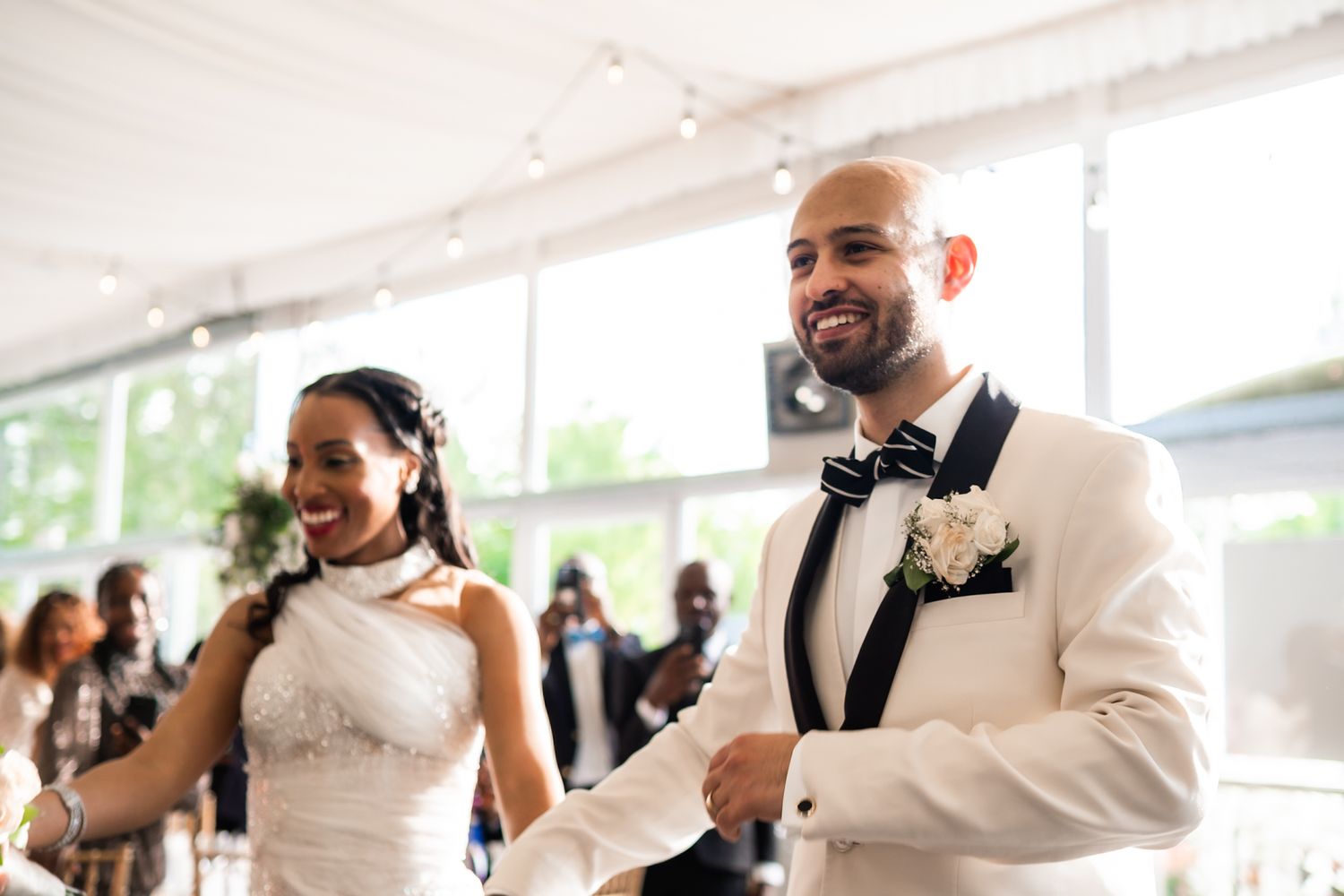 A joyful wedding celebration with a couple dancing in formal attire at an indoor reception venue.