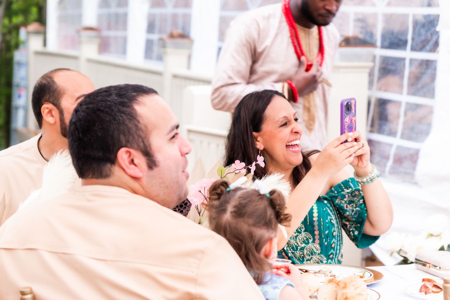 Wedding guests at a reception table taking photos and enjoying the celebration.