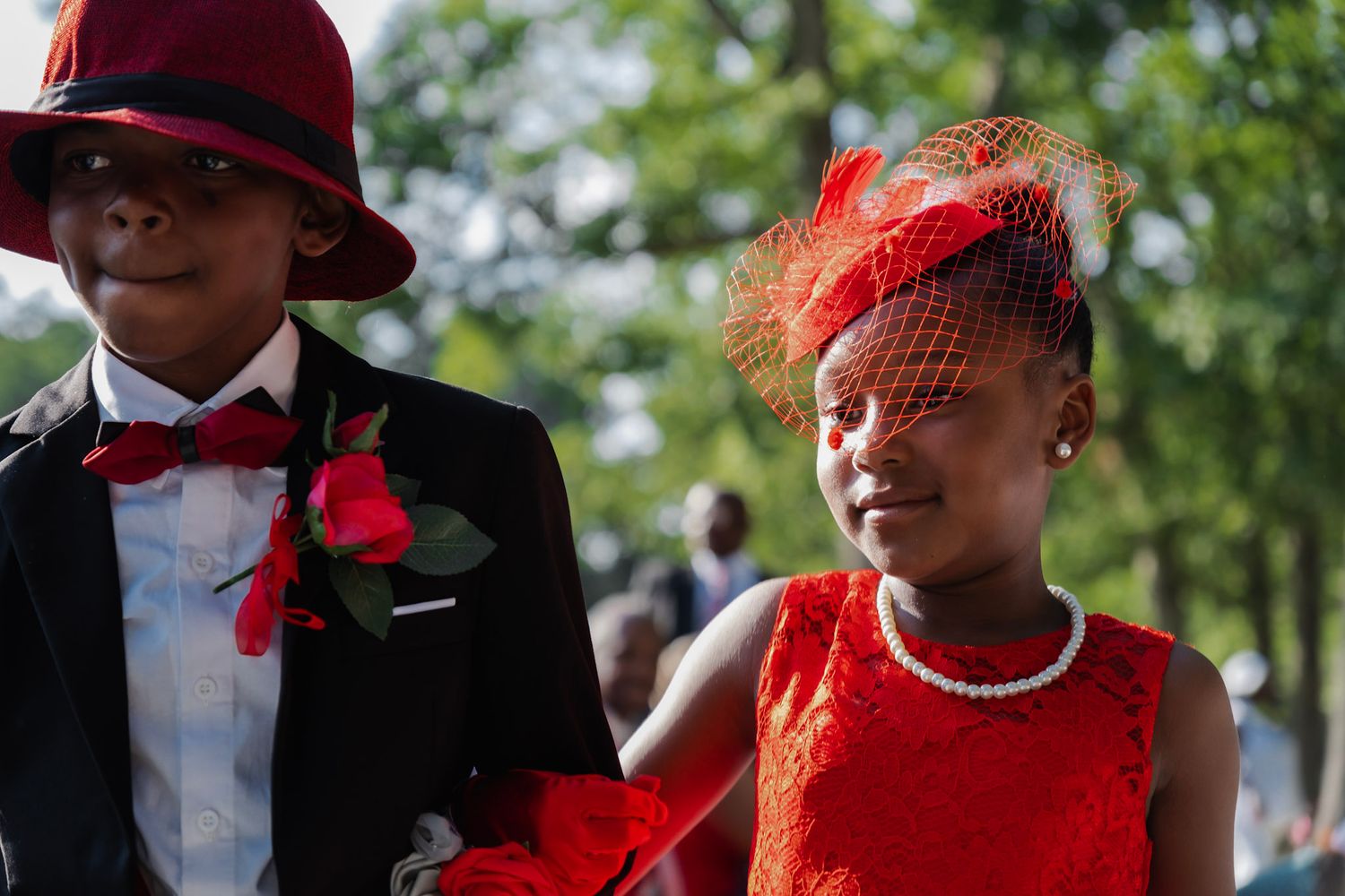 Young wedding attendees in formal red and black attire with matching accessories.