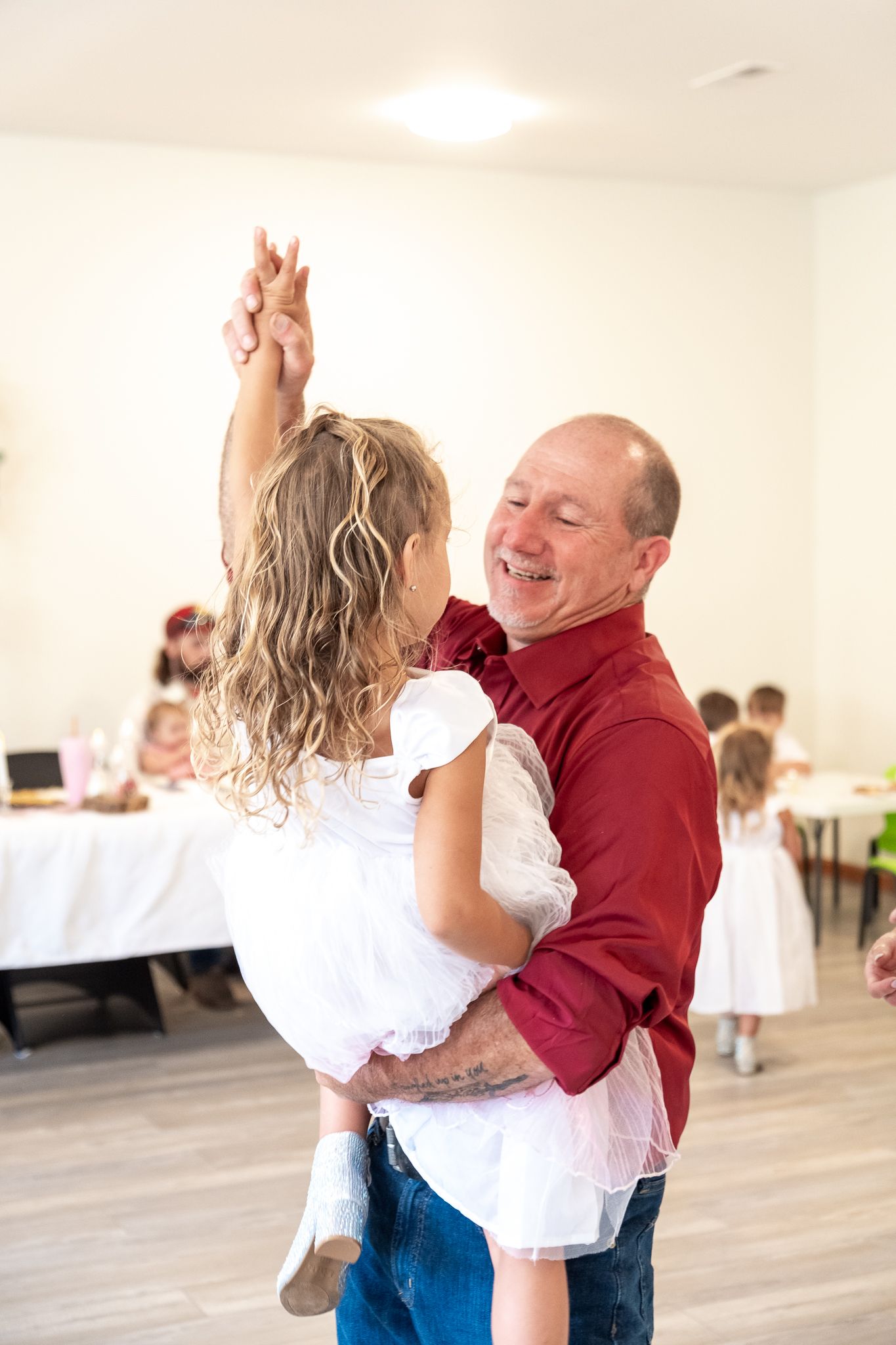 Dancers practice partner dancing on a wooden floor in a bright studio space.