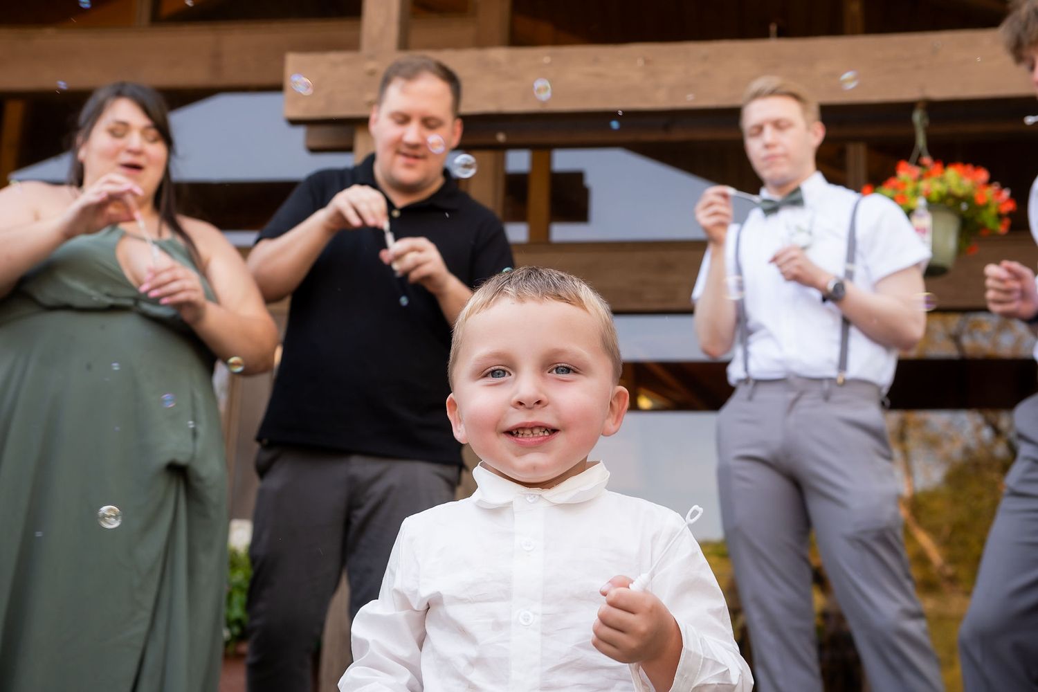 Wedding guests blowing bubbles during celebration outside rustic venue.