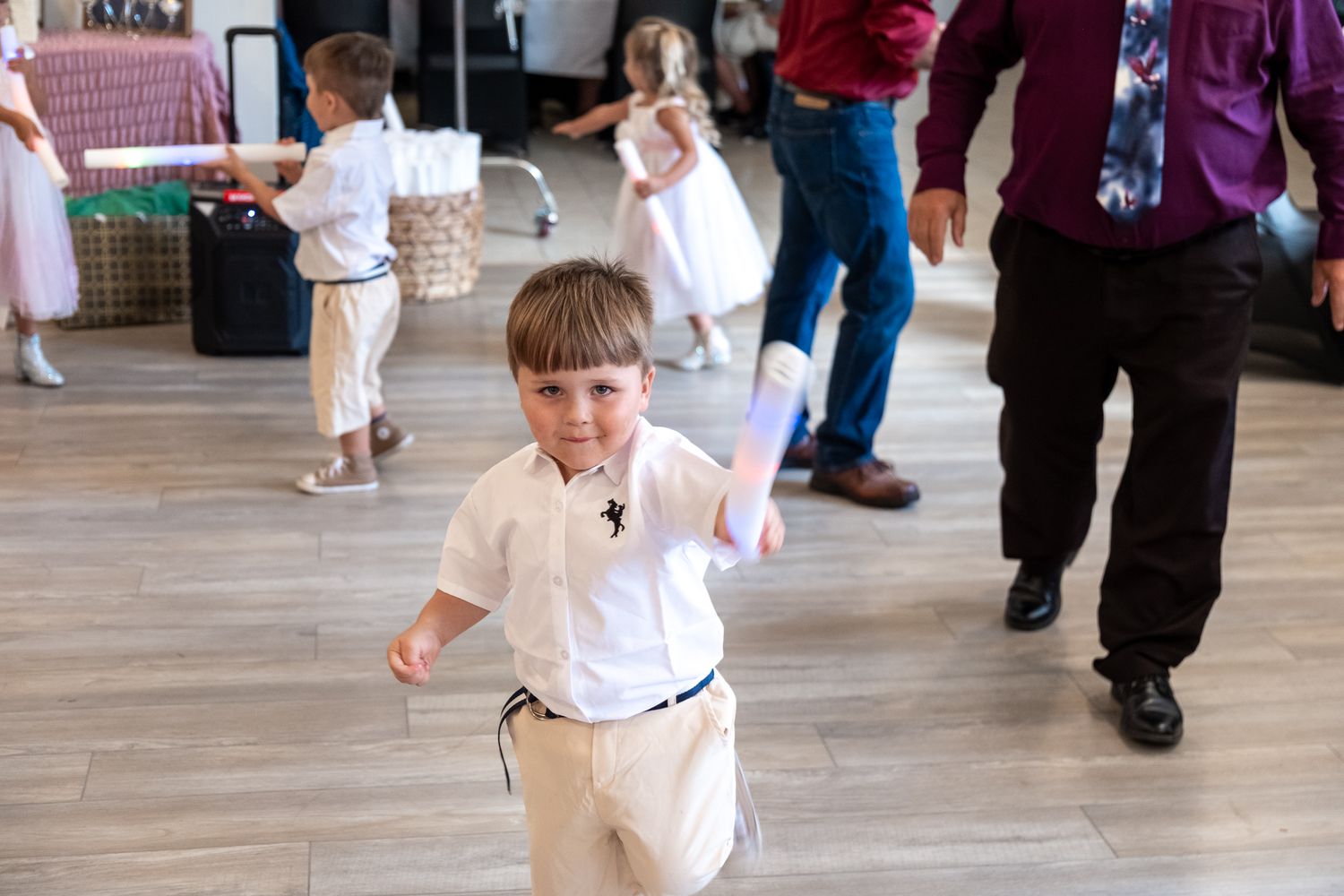 Young students in white uniforms practice martial arts moves during a karate class on a wooden floor.