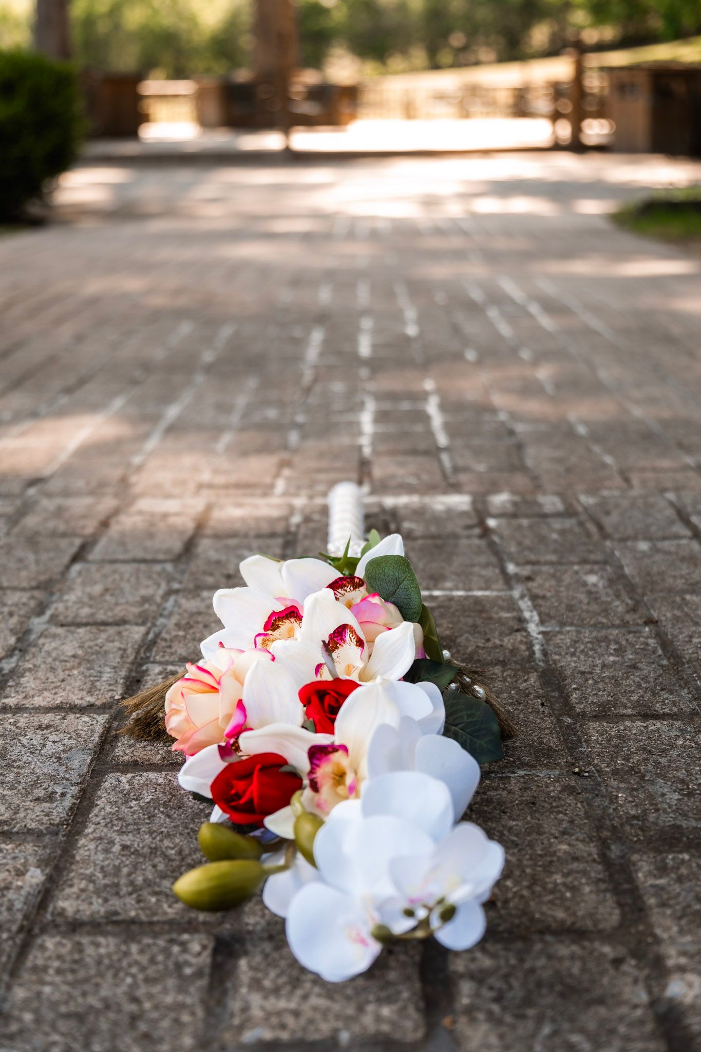 Beautiful floral arrangement with orchids and roses lying on stone pavement.