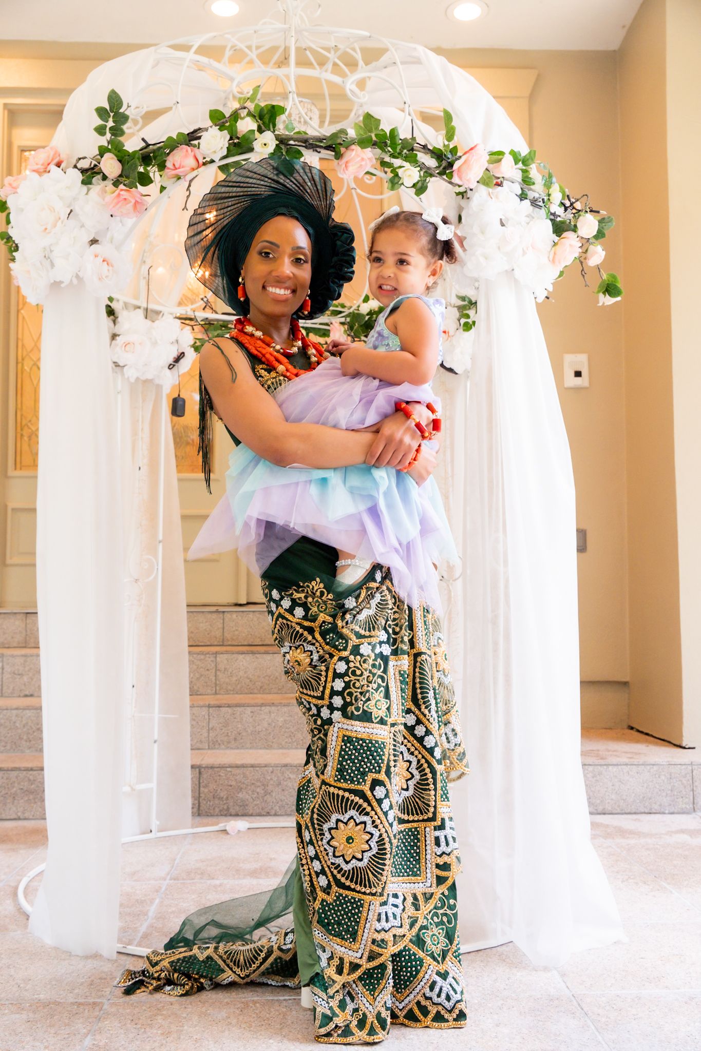 A beautiful wedding arch decorated with white flowers and greenery frames a tender moment.
